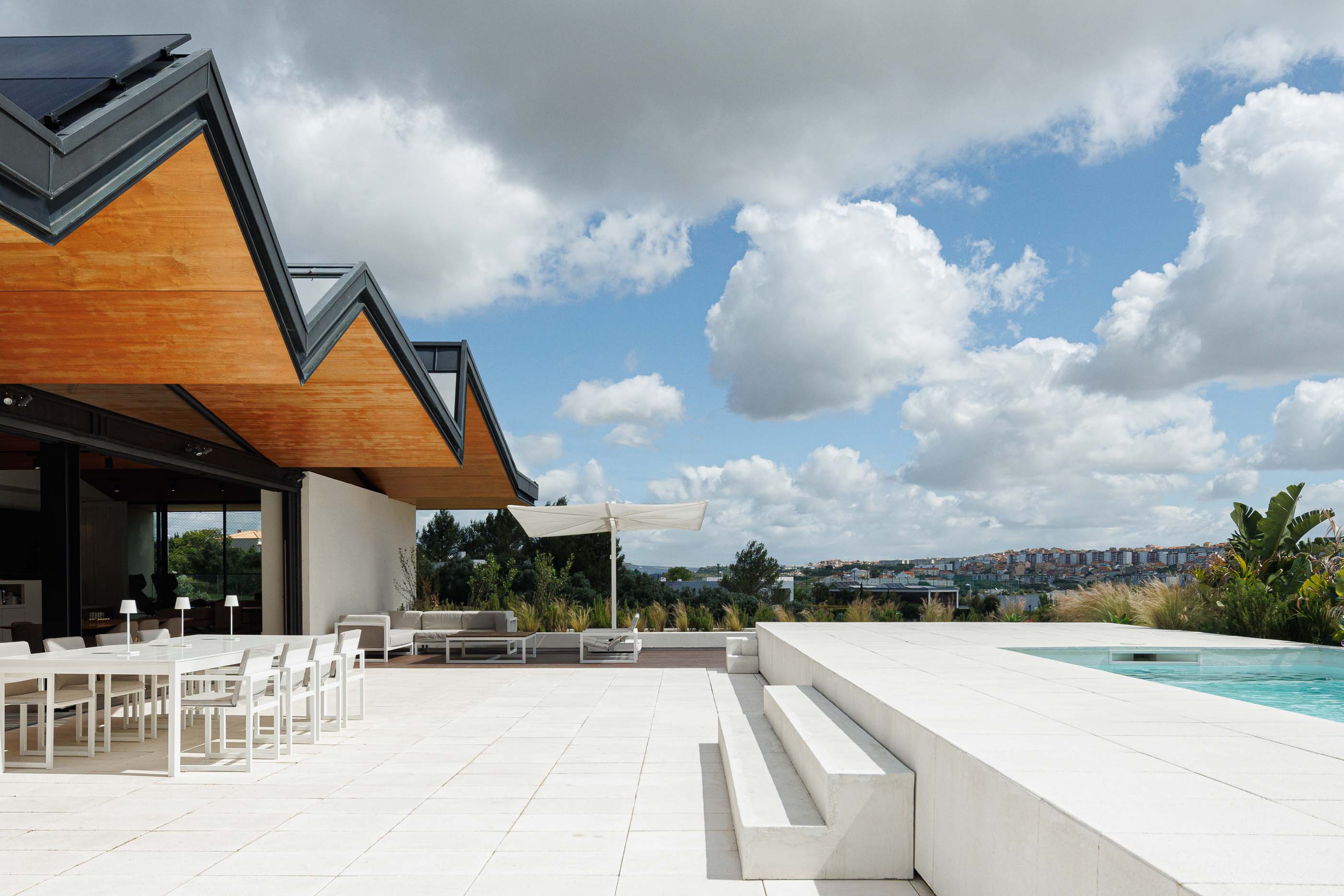 Terraço: Espaço exterior com piscina, zona de estar, mesa de jantar e telhado em madeira. — Casa dos Alcoutins arquitetura Paulo Martins Arquitectura e Design em Lisboa