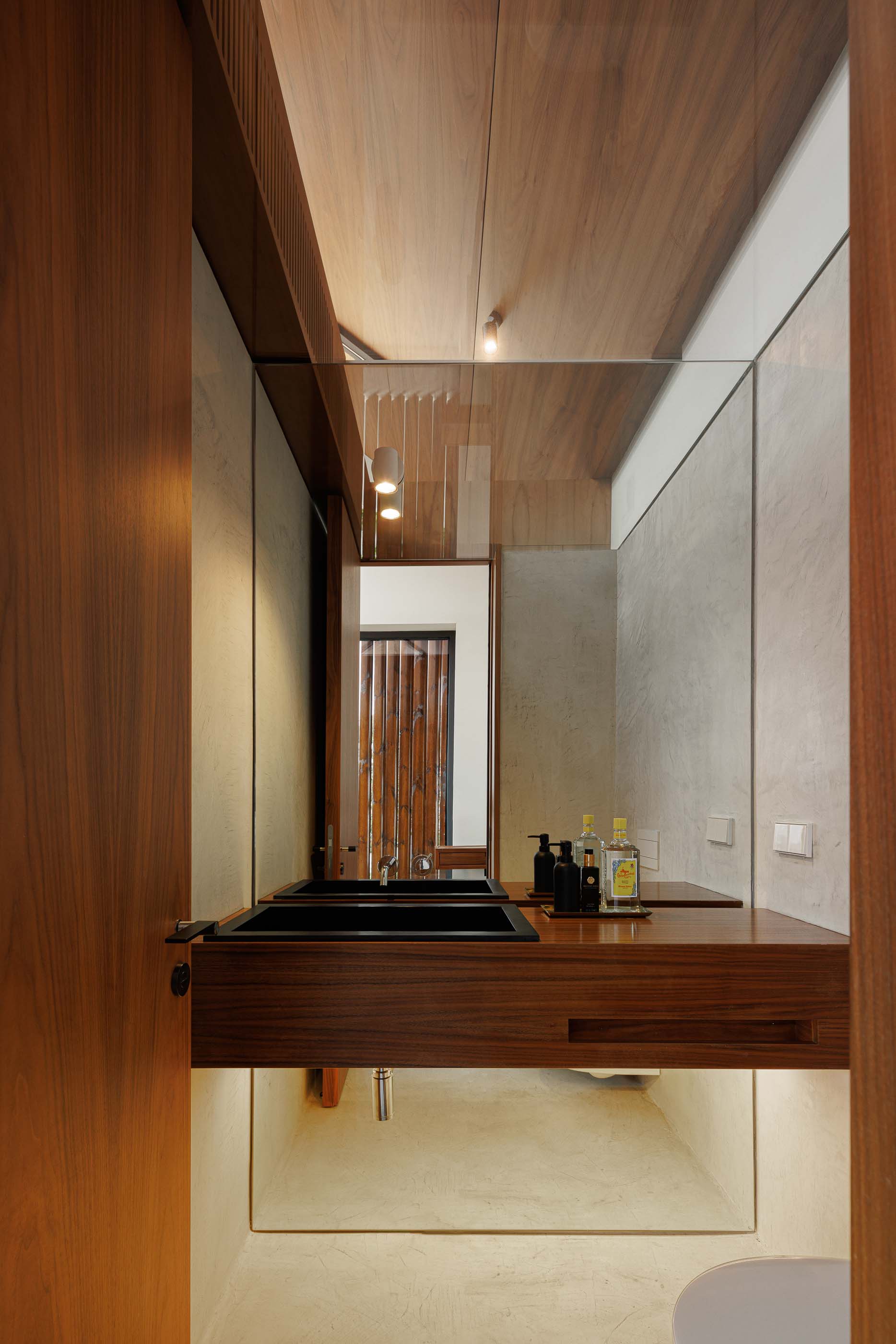 Casa de banho: Interior com lavatório duplo em madeira escura, espelho amplo e iluminação indireta. — Casa dos Alcoutins arquitetura Paulo Martins Arquitectura e Design em Lisboa