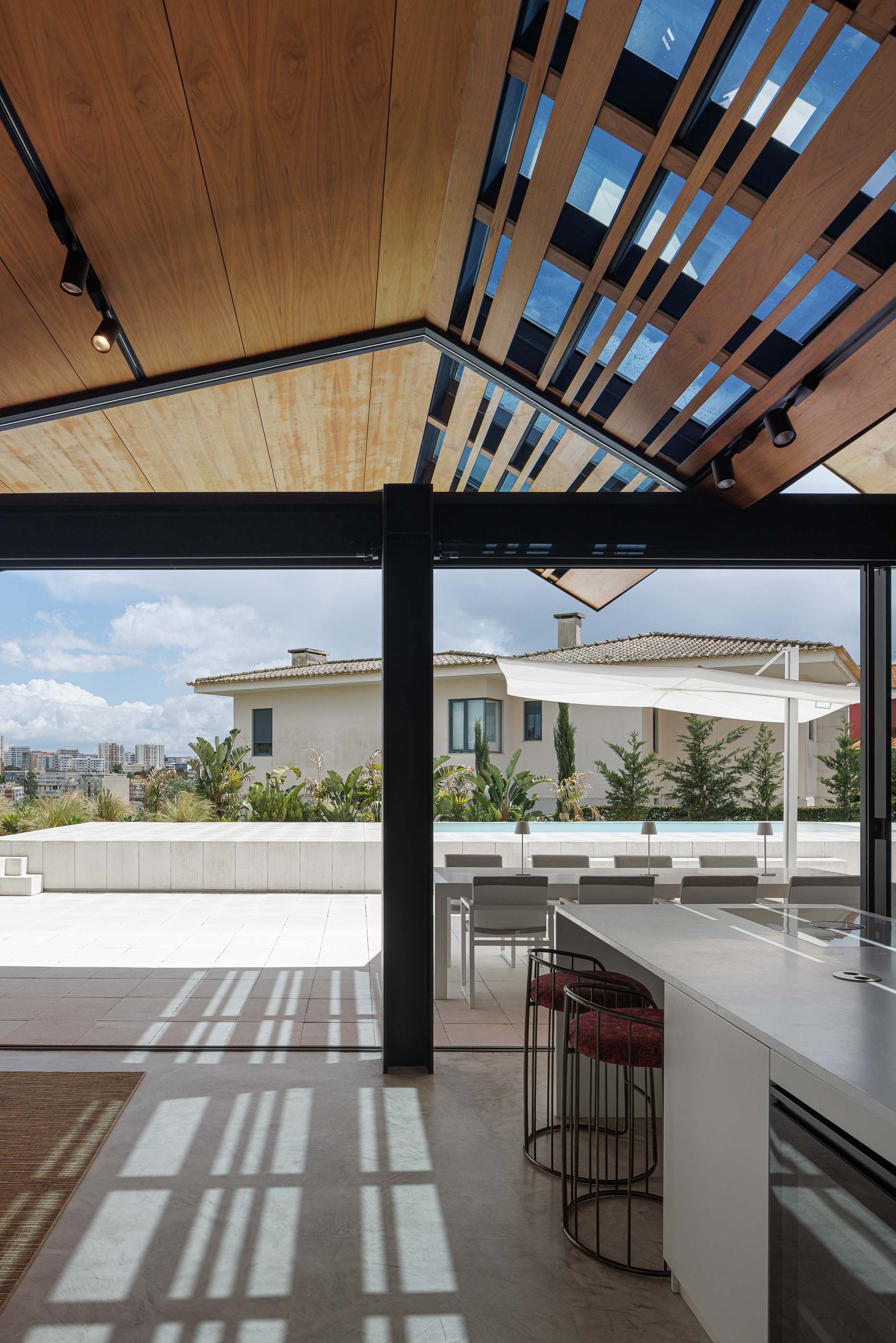 Sala de jantar: Interior com teto em madeira, iluminação direcionada, mesa de jantar e acesso à sala de estar. — Casa dos Alcoutins arquitetura Paulo Martins Arquitectura e Design em Lisboa