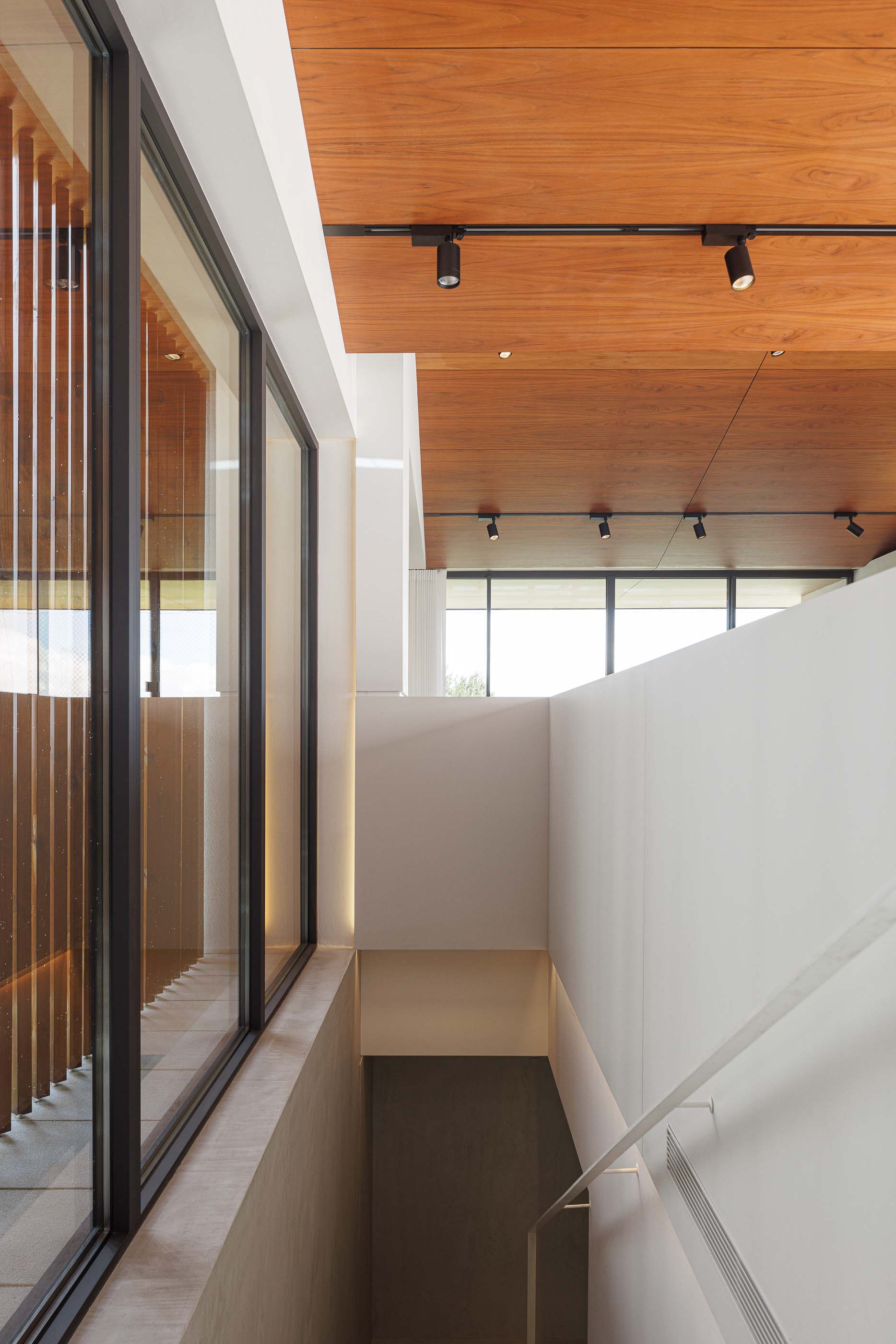 Escadas: Escadas em betão com paredes texturadas e porta de acesso a um quarto com pavimento em madeira. — Casa dos Alcoutins arquitetura Paulo Martins Arquitectura e Design em Lisboa