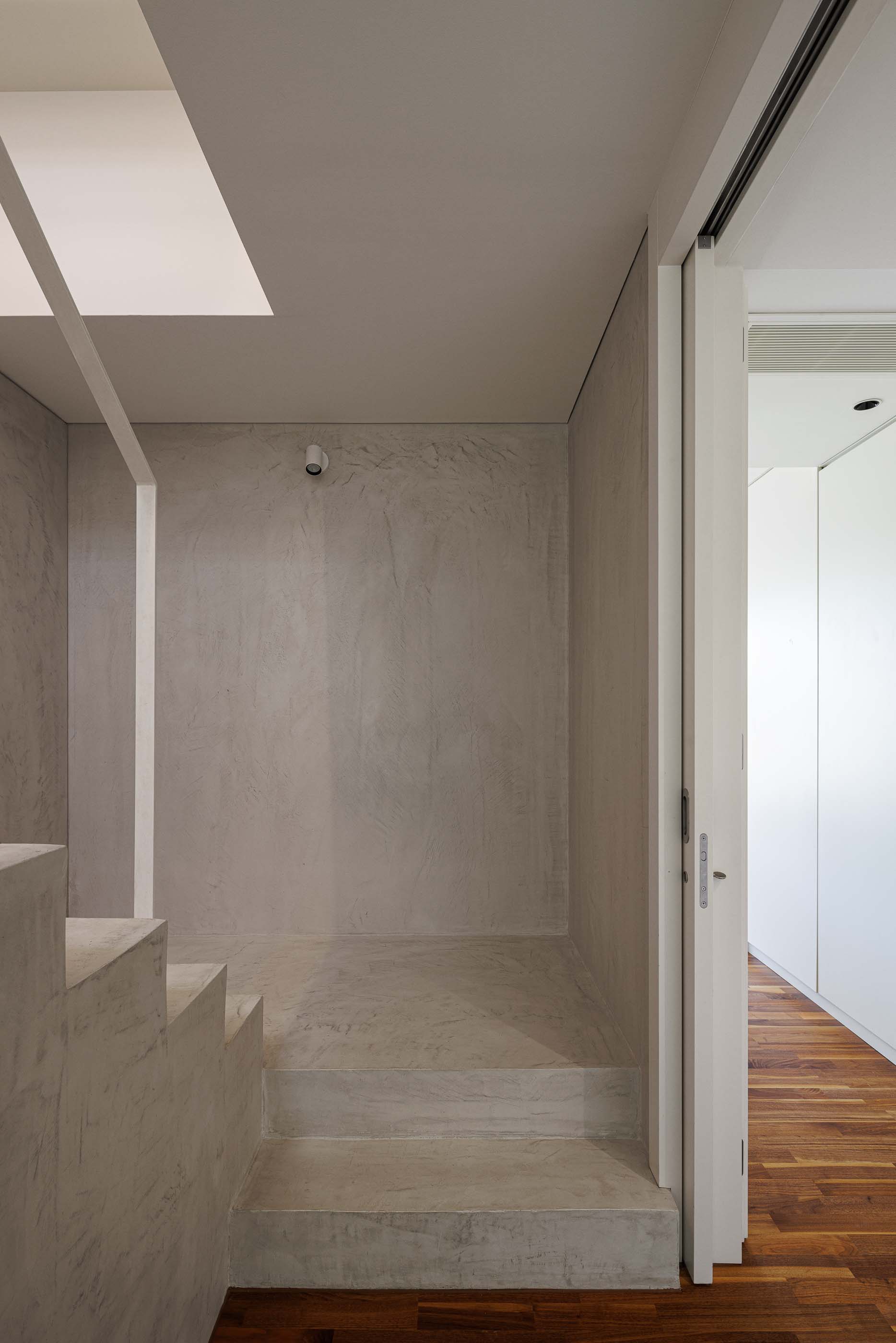 Escadas: Escadas com paredes brancas, iluminação embutida e pavimento em betão. — Casa dos Alcoutins arquitetura Paulo Martins Arquitectura e Design em Lisboa