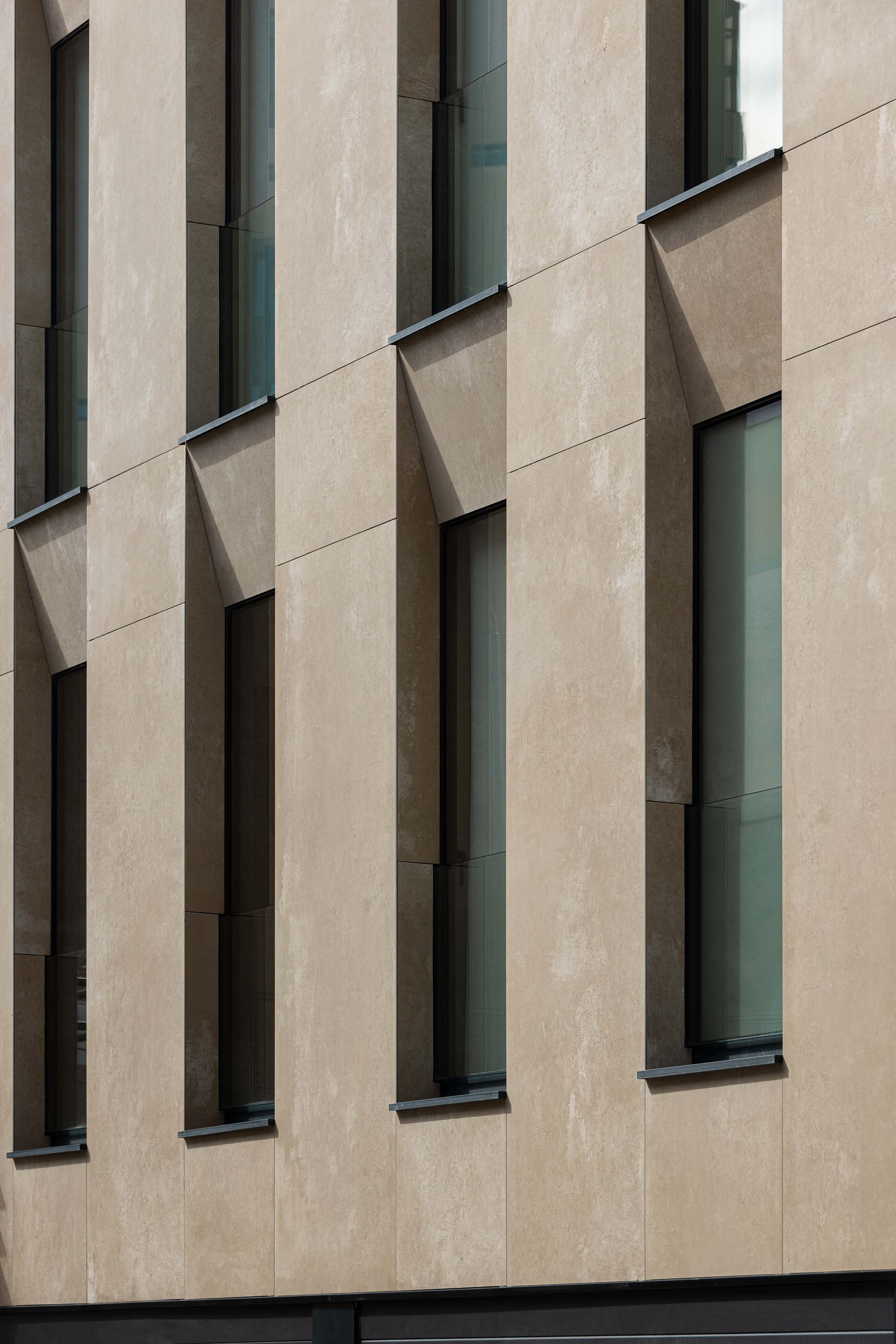 Fachada: Detalhe das janelas verticais em betão texturado, com caixilharia preta. — Reabilitação Poveira - Edifício FS11 arquitetura Urbanpolis em Póvoa de Varzim