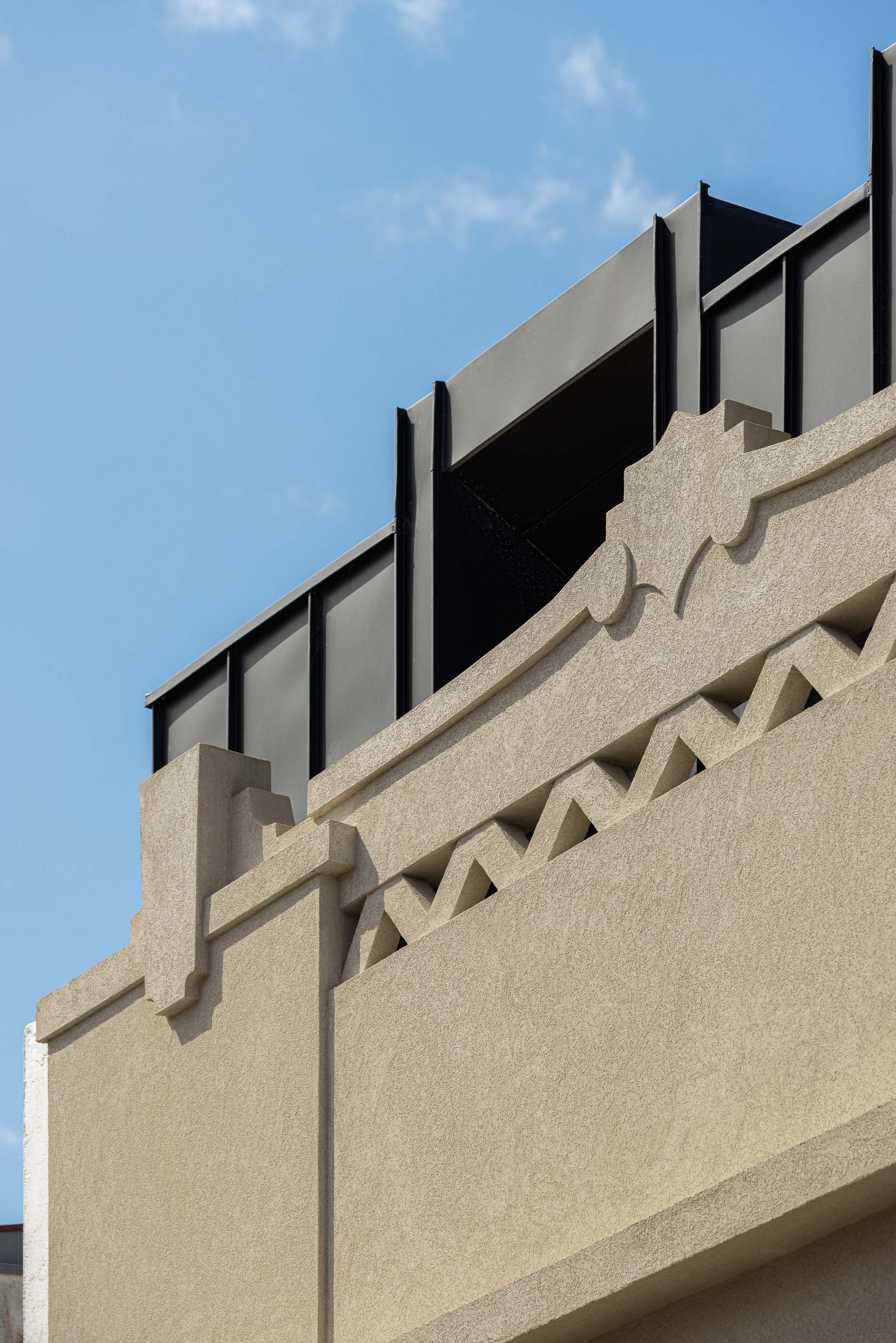 Fachada: Detalhe da cornija do edifício antigo, com elementos decorativos geométricos e cobertura moderna. — Reabilitação Poveira - Edifício FS11 arquitetura Urbanpolis em Póvoa de Varzim