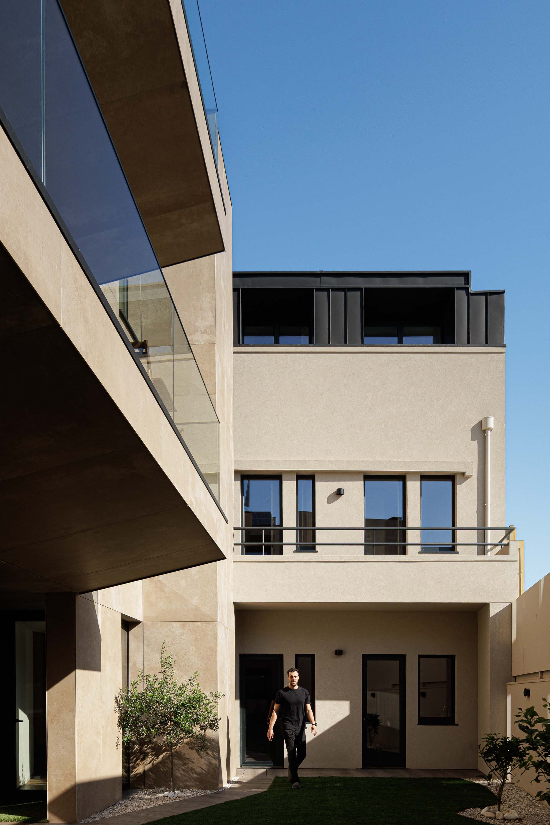 Exterior: Pátio interior com relvado, oliveira e vista para as varandas do edifício. — Reabilitação Poveira - Edifício FS11 arquitetura Urbanpolis em Póvoa de Varzim