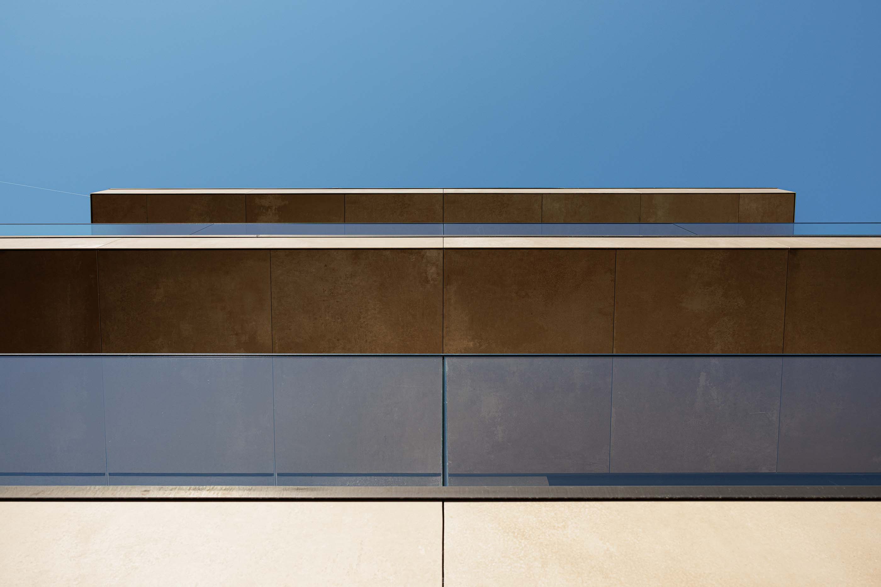 Exterior: Detalhe da fachada com varanda envidraçada e revestimento em tons terra. — Reabilitação Poveira - Edifício FS11 arquitetura Urbanpolis em Póvoa de Varzim