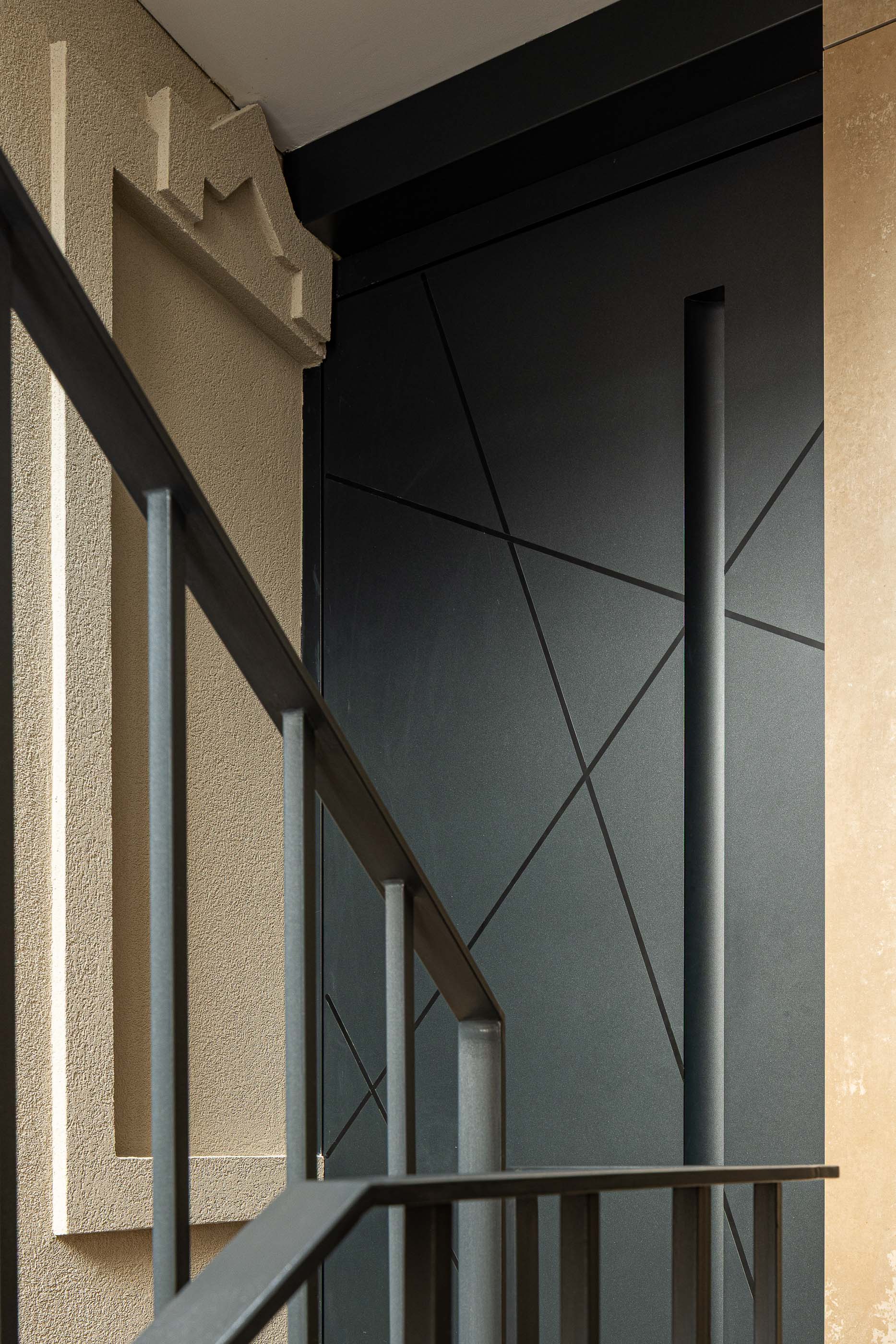 Escada: Detalhe da grade metálica preta, porta moderna e elementos decorativos na parede. — Reabilitação Poveira - Edifício FS11 arquitetura Urbanpolis em Póvoa de Varzim