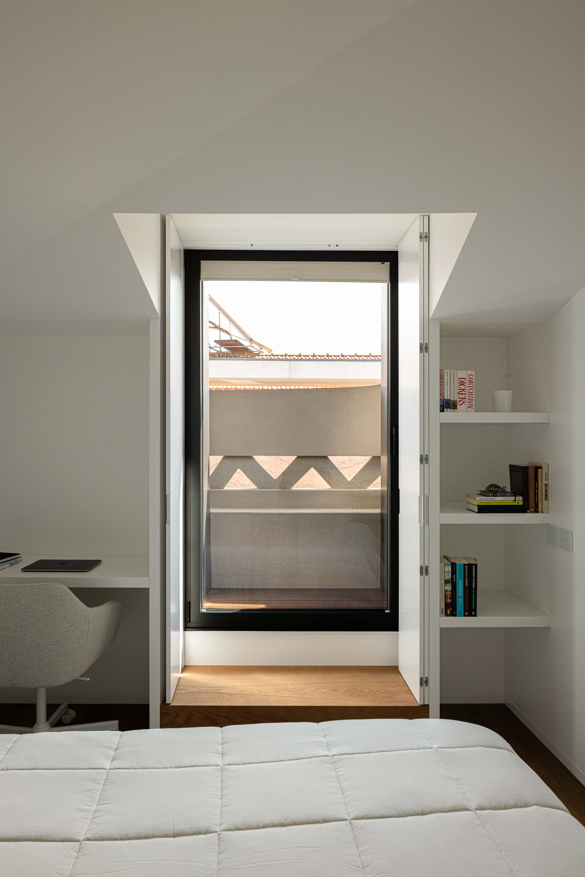 Quarto: Quarto com secretária, estantes embutidas e vista para o exterior. — Reabilitação Poveira - Edifício FS11 arquitetura Urbanpolis em Póvoa de Varzim