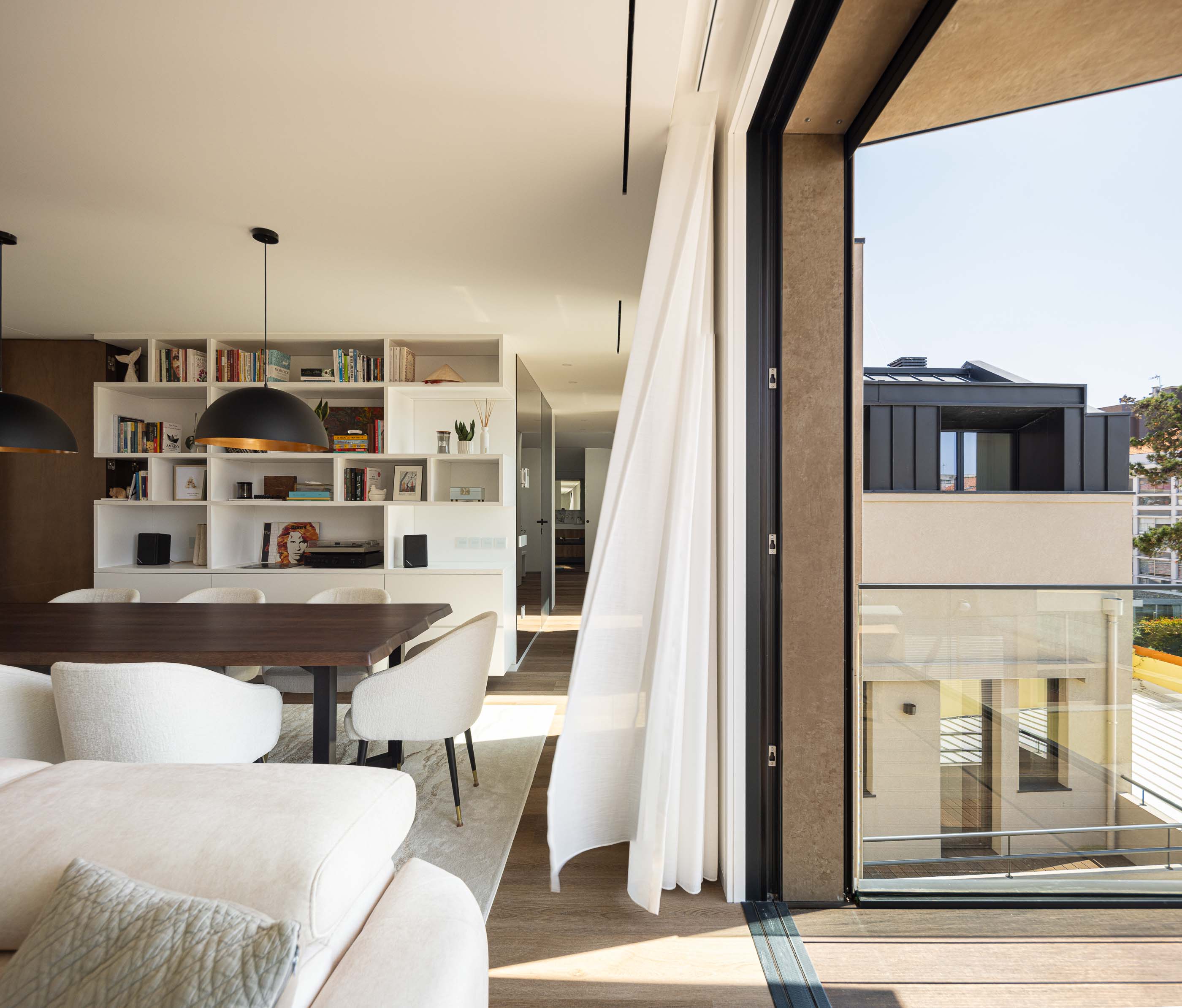 Sala de estar: Sala de estar com mesa de jantar, estantes embutidas e acesso à varanda. — Reabilitação Poveira - Edifício FS11 arquitetura Urbanpolis em Póvoa de Varzim