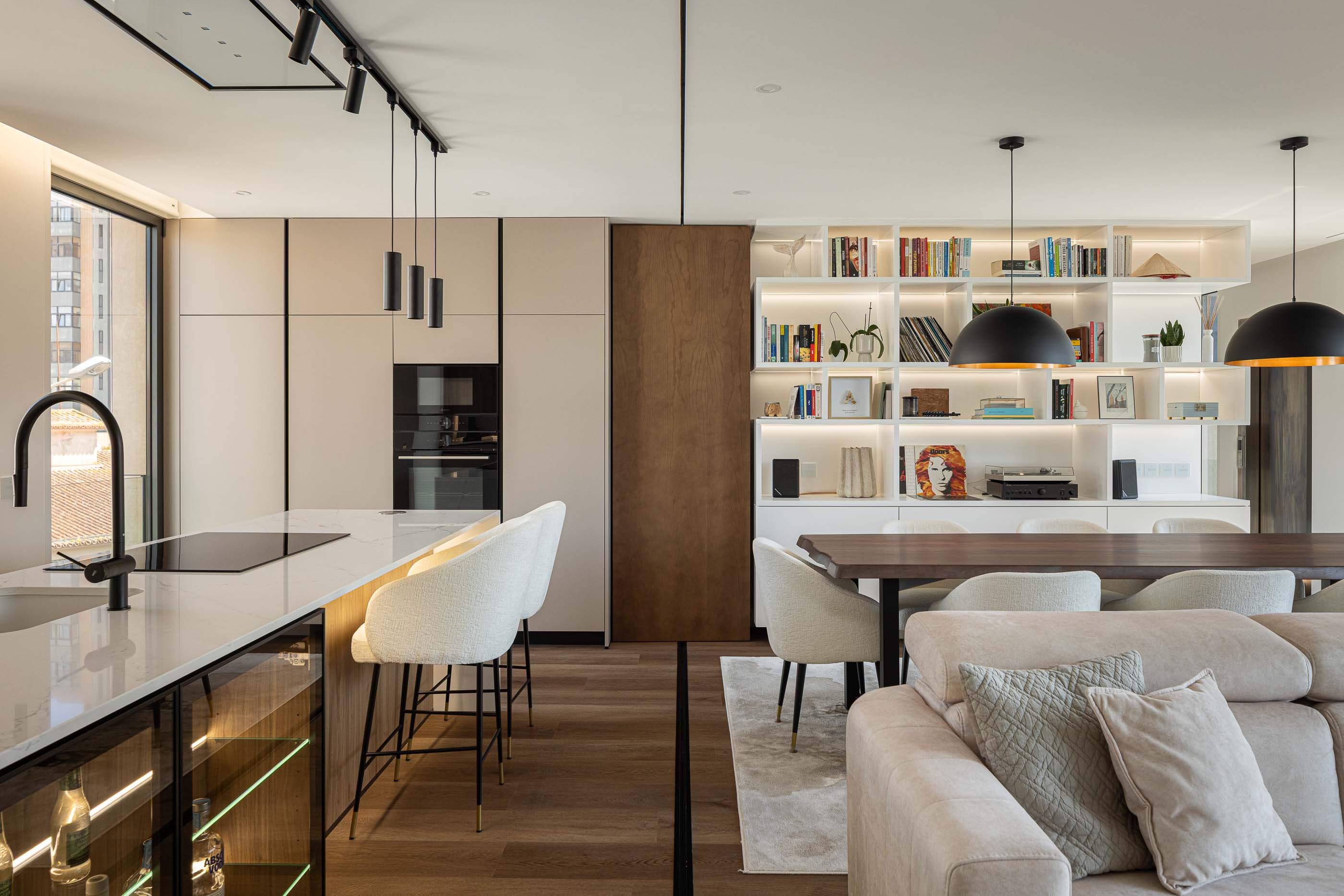 Sala de estar: Espaço amplo com cozinha integrada, ilha central, sofás e mesa de jantar. — Reabilitação Poveira - Edifício FS11 arquitetura Urbanpolis em Póvoa de Varzim