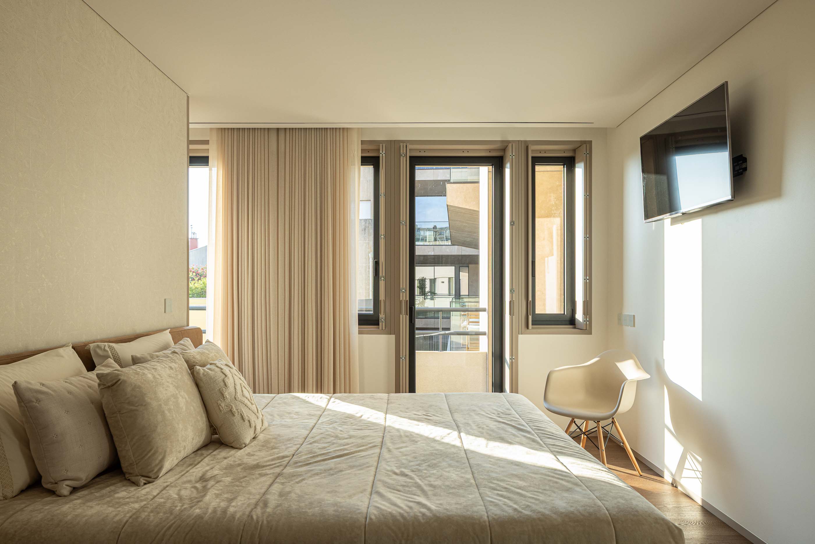 Quarto: Quarto com cama de casal, televisão e acesso à varanda. — Reabilitação Poveira - Edifício FS11 arquitetura Urbanpolis em Póvoa de Varzim