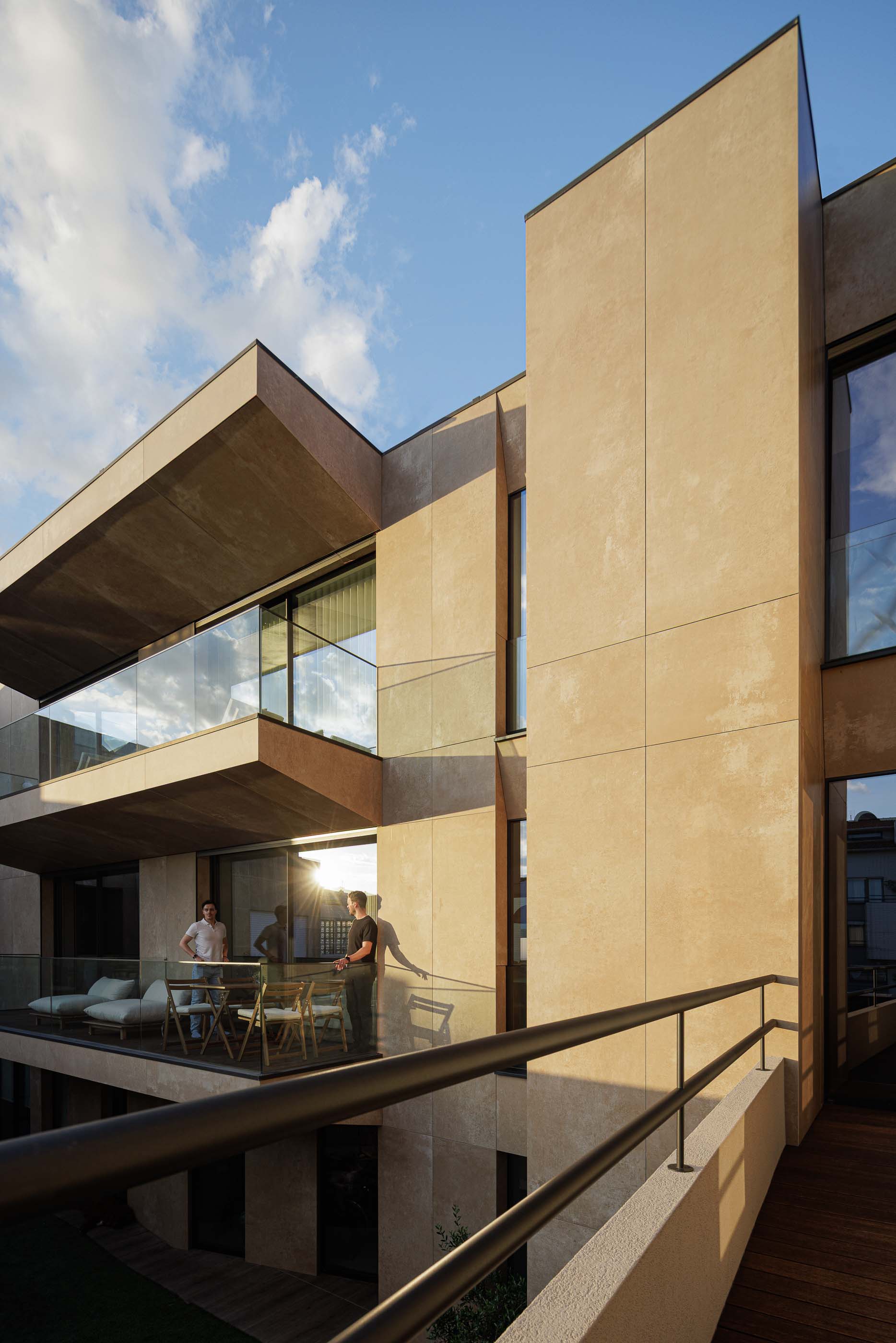 Exterior: Edifício com varandas envidraçadas, jardim relvado e pavimento em madeira. — Reabilitação Poveira - Edifício FS11 arquitetura Urbanpolis em Póvoa de Varzim
