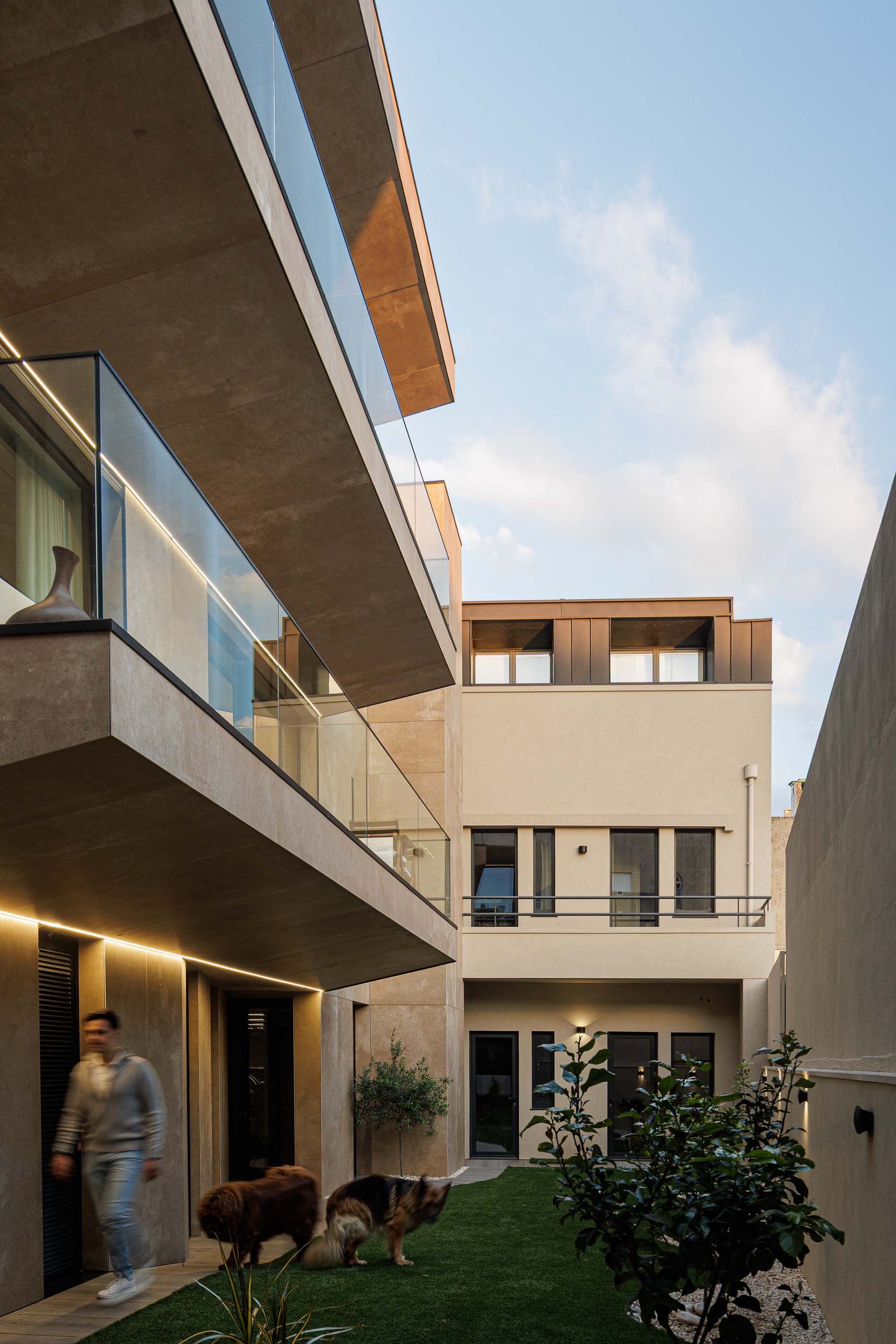 Fachada: Edifício moderno com fachada em tons terra, janelas verticais e iluminação exterior. — Reabilitação Poveira - Edifício FS11 arquitetura Urbanpolis em Póvoa de Varzim