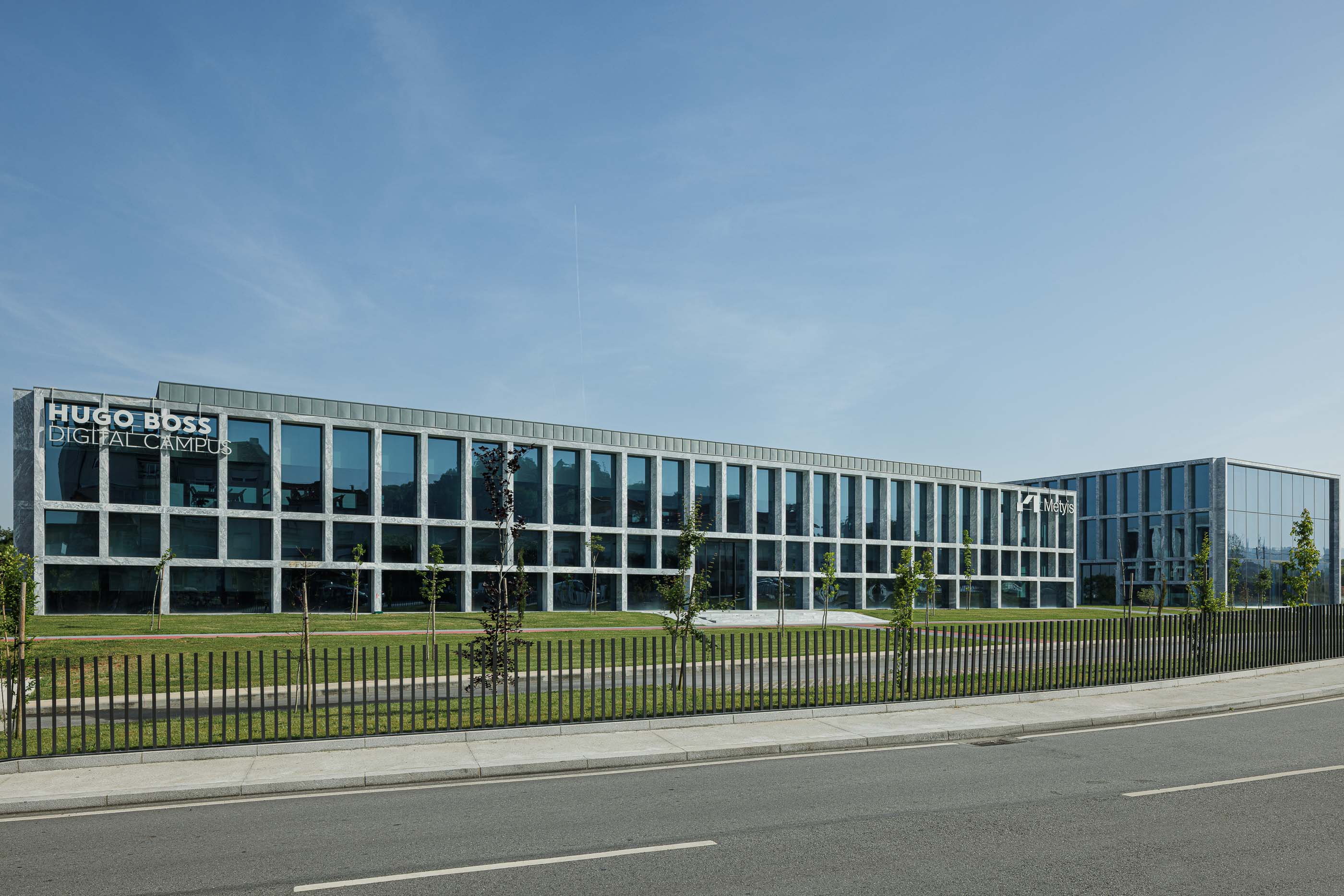 Edifício: Fachada do edifício Hugo Boss Digital Campus, com estrutura em mármore e amplas janelas envidraçadas. — Metyis Digital Campus arquitetura UNUM - Oficina de Arquitetura em Gondomar