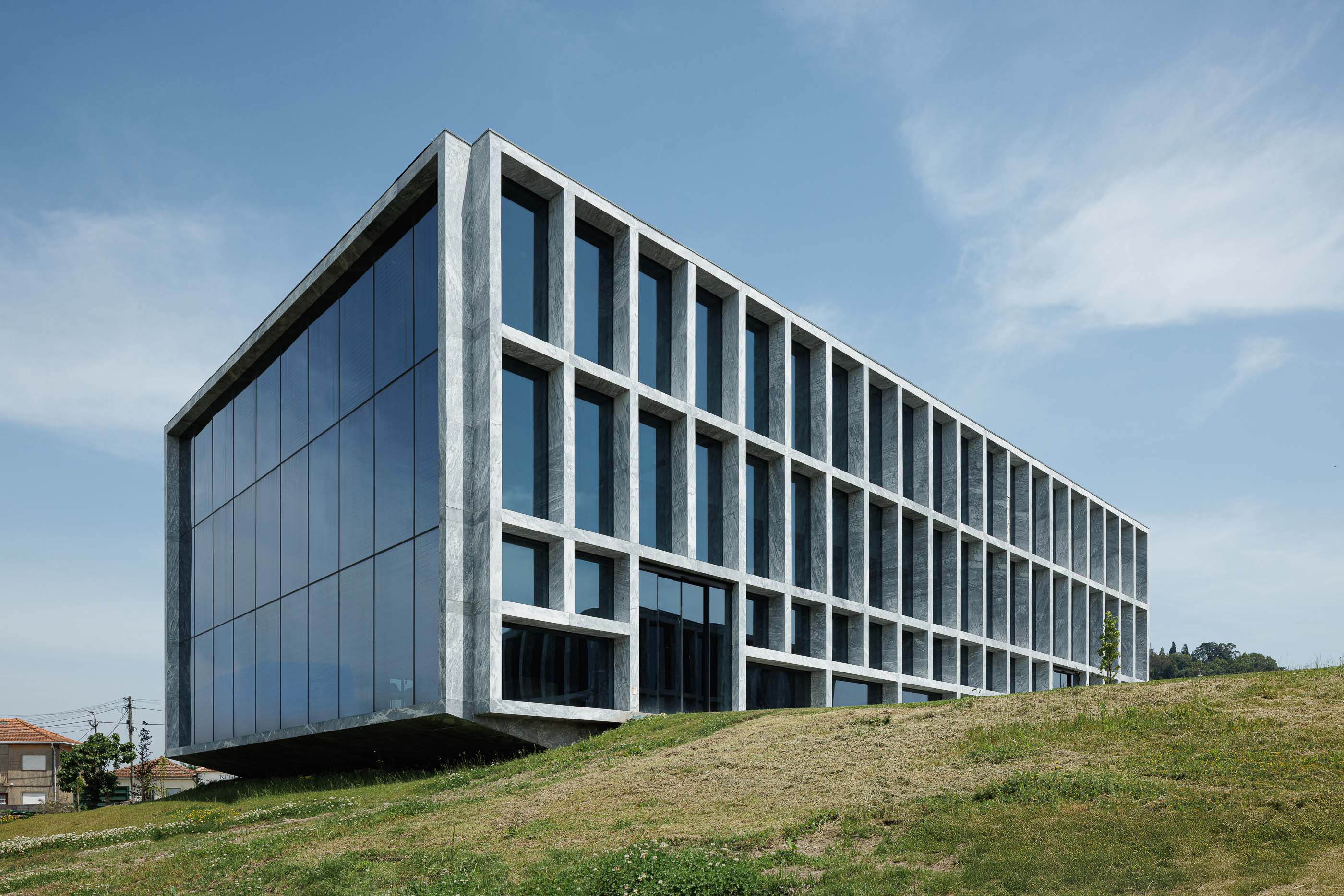 Edifício: Edifício com fachada em mármore e janelas, assente num terreno relvado. Arquitetura moderna e minimalista. — Metyis Digital Campus arquitetura UNUM - Oficina de Arquitetura em Gondomar