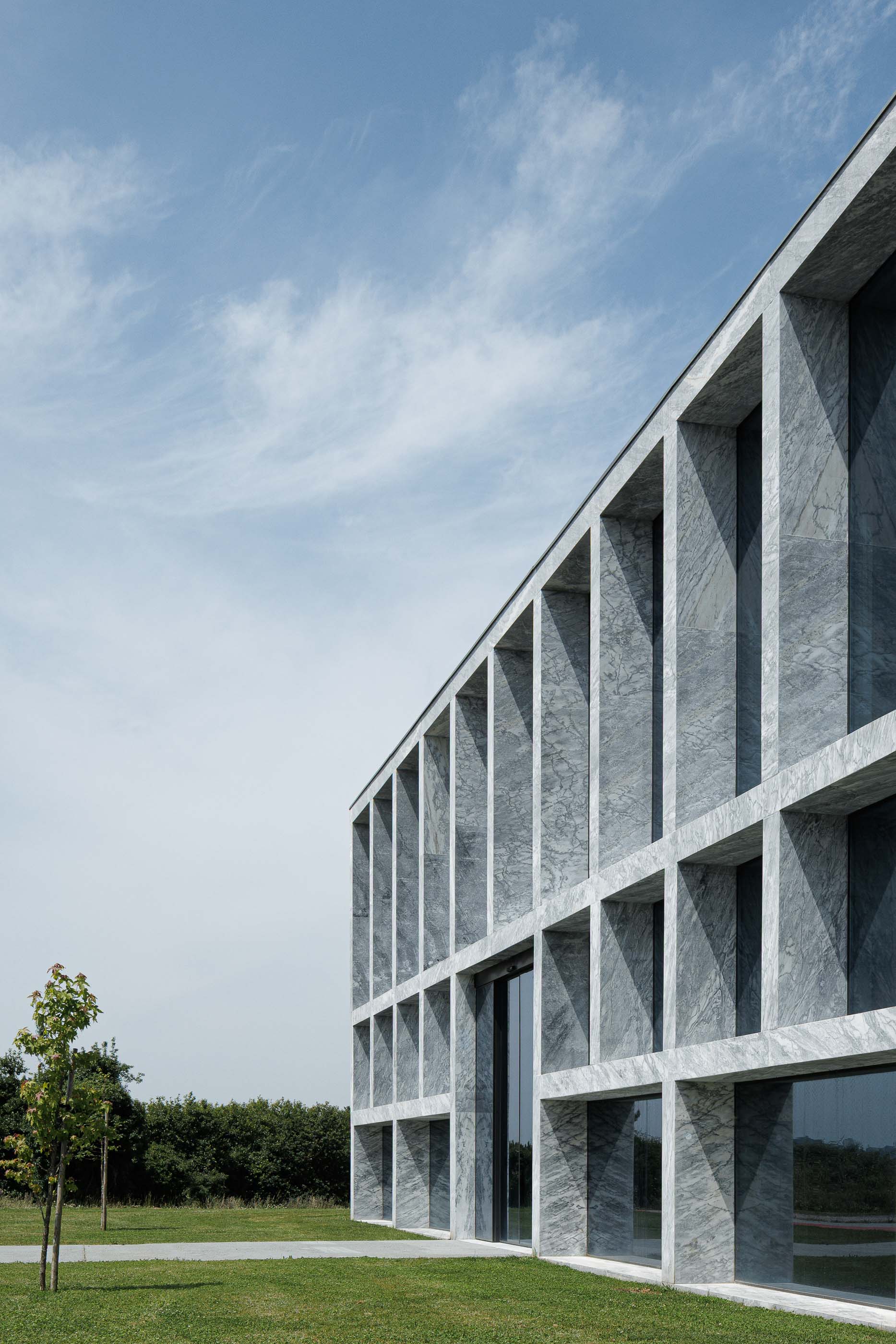 Edifício: Detalhe da fachada em mármore com janelas, destacando a simetria e o design minimalista. — Metyis Digital Campus arquitetura UNUM - Oficina de Arquitetura em Gondomar