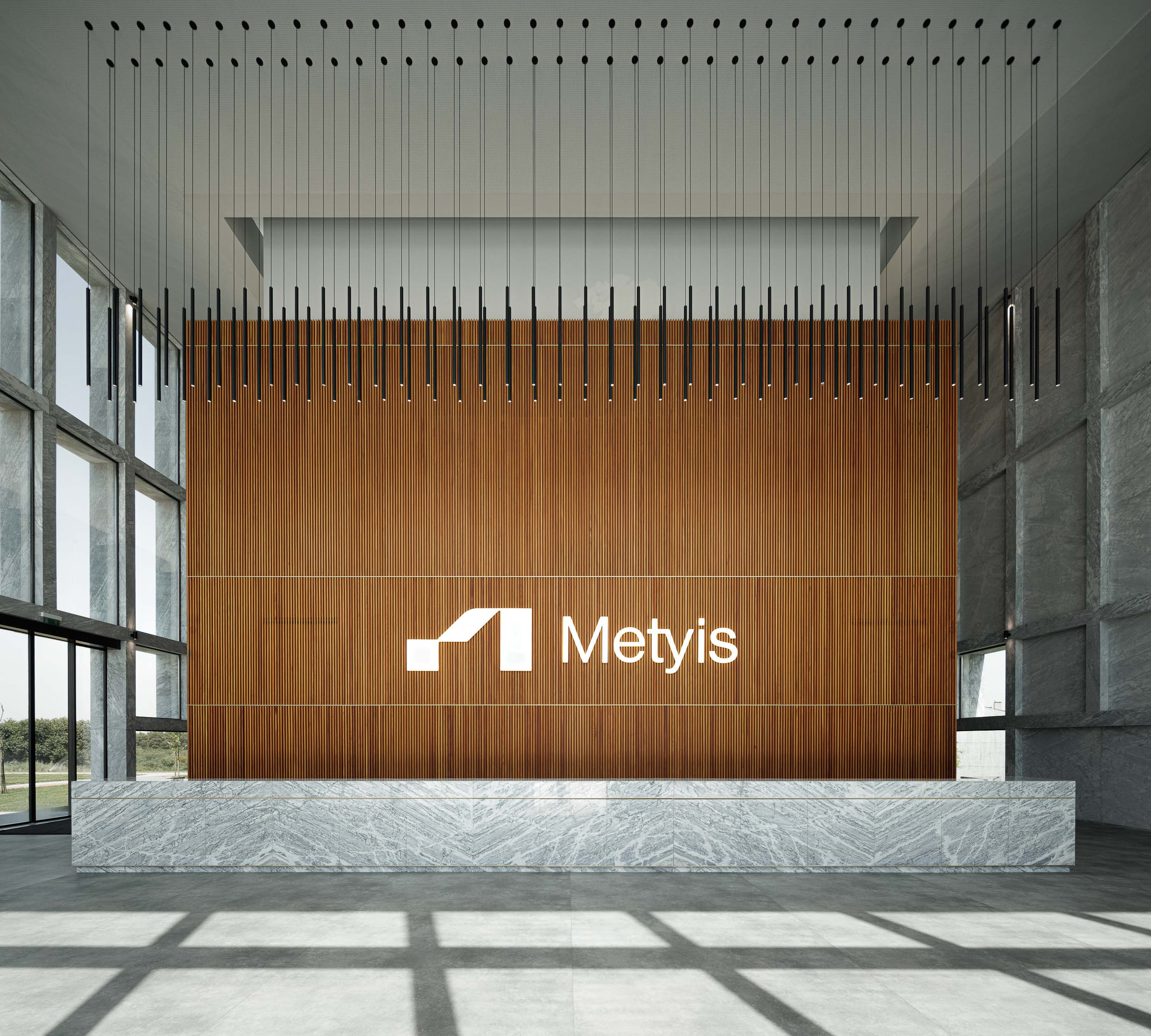 Hall de entrada: Recepção com balcão em mármore, parede em madeira ripada e candeeiros suspensos. — Metyis Digital Campus arquitetura UNUM - Oficina de Arquitetura em Gondomar