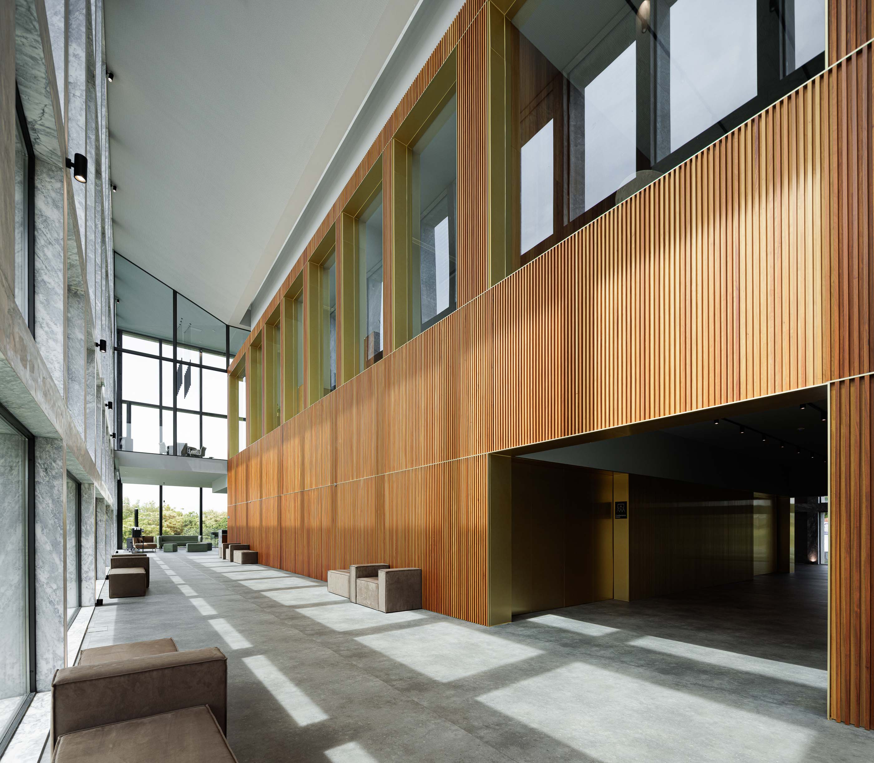 Corredor: Corredor com pavimento em cimento afagado, paredes em madeira ripada e janelas amplas. — Metyis Digital Campus arquitetura UNUM - Oficina de Arquitetura em Gondomar