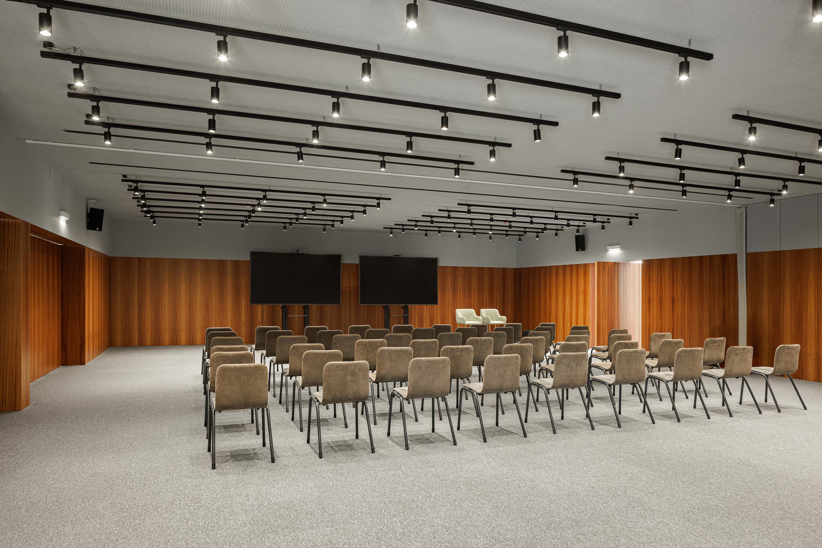 Sala de reuniões: Sala de reuniões com cadeiras, mesas, alcatifa e duas telas grandes. — Metyis Digital Campus arquitetura UNUM - Oficina de Arquitetura em Gondomar