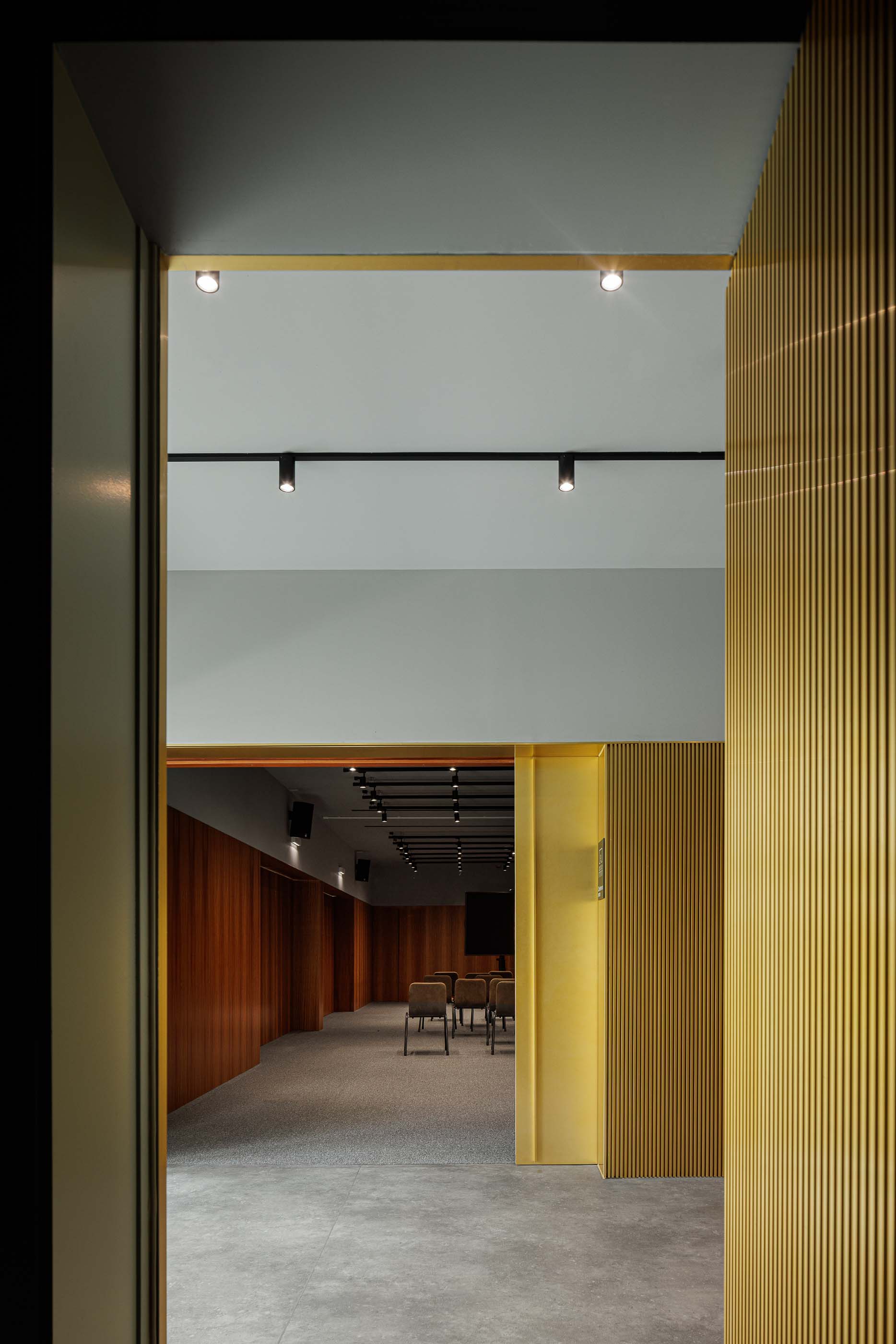 Corredor: Vista da entrada da sala de reuniões com detalhes em dourado e iluminação embutida. — Metyis Digital Campus arquitetura UNUM - Oficina de Arquitetura em Gondomar