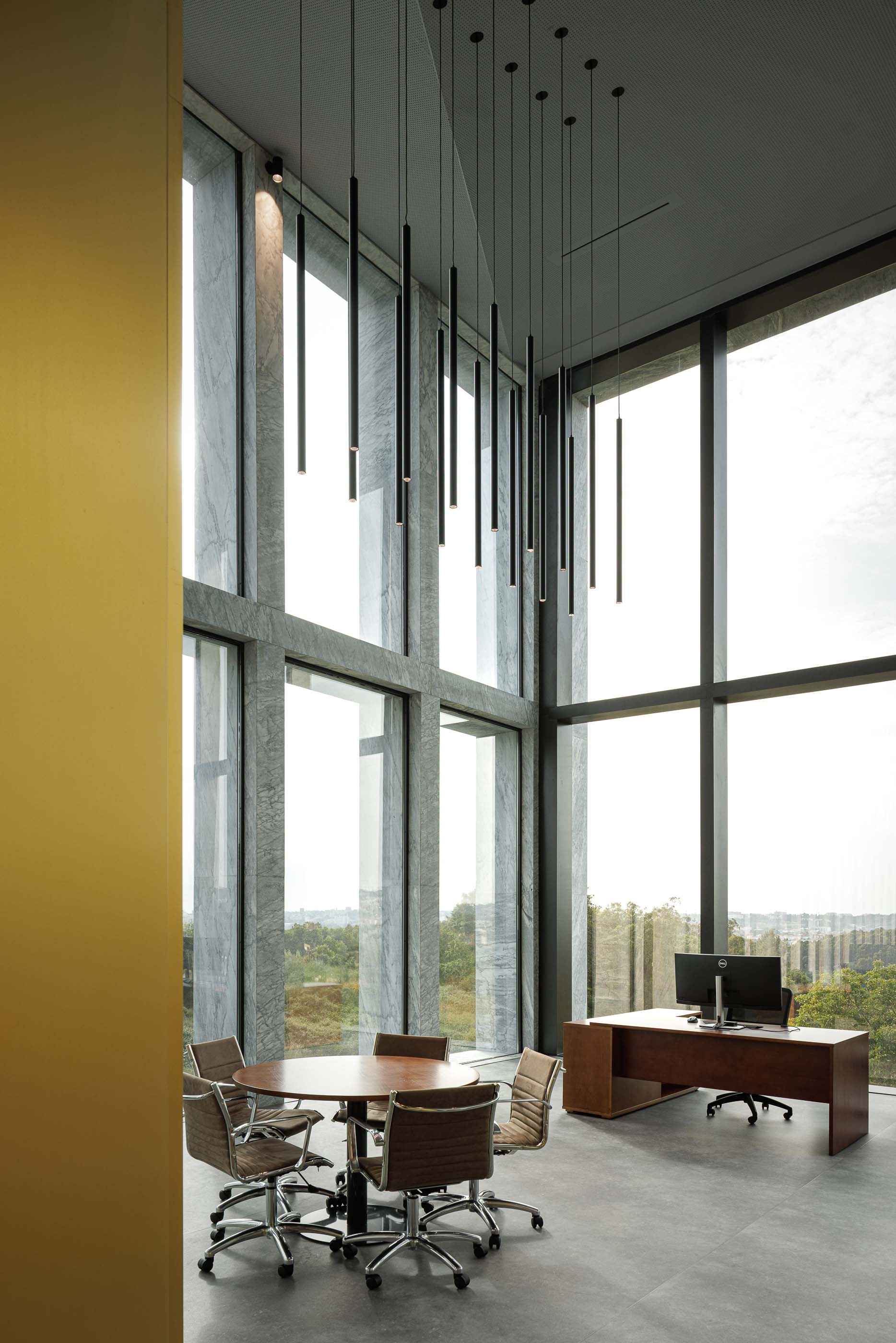 Escritório: Espaço de escritório com mesa de reuniões, cadeiras, secretária e vista para o exterior. — Metyis Digital Campus arquitetura UNUM - Oficina de Arquitetura em Gondomar