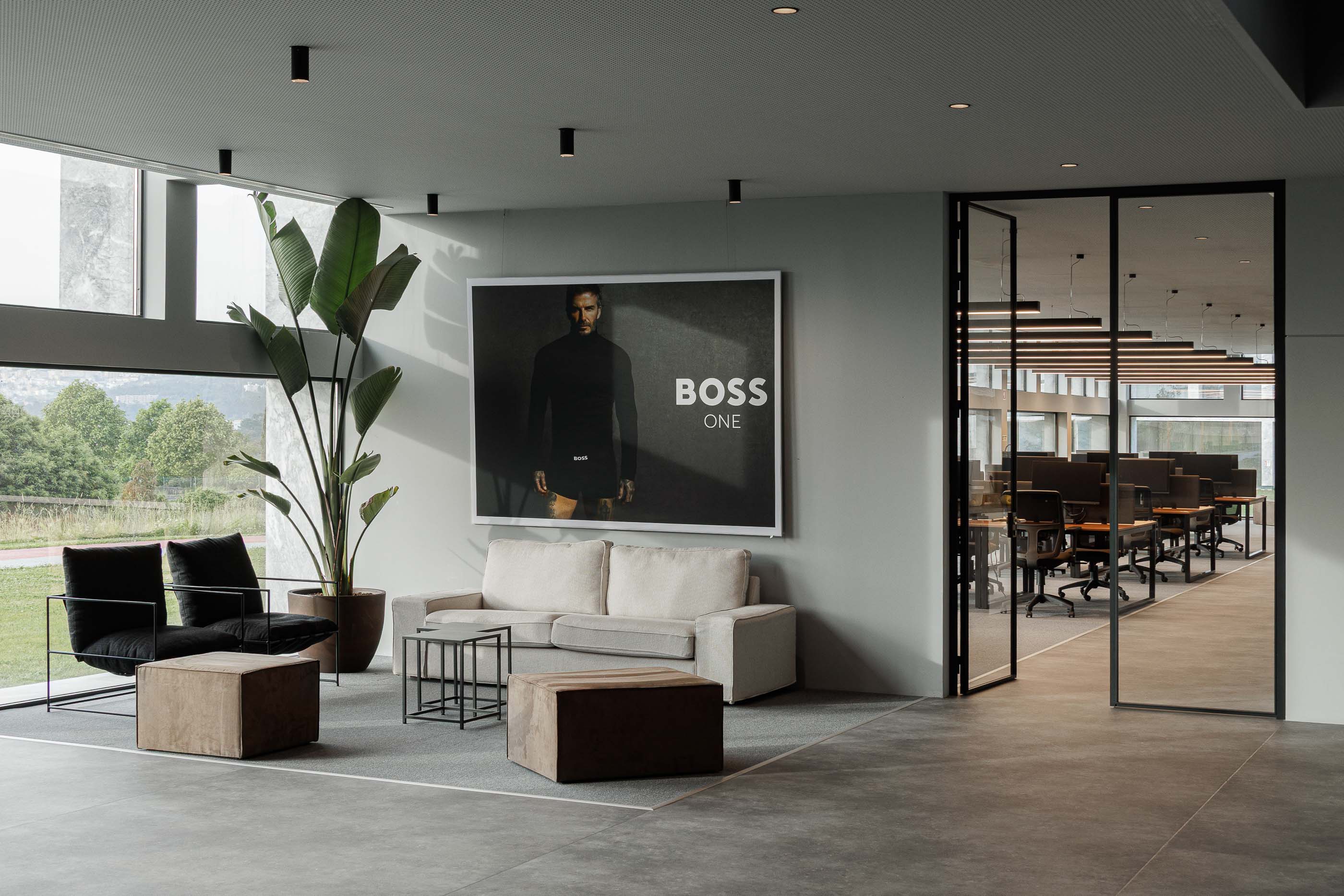 Zona de descanso: Zona de descanso com sofás, cadeirões, mesas de apoio e vista para o escritório. — Metyis Digital Campus arquitetura UNUM - Oficina de Arquitetura em Gondomar