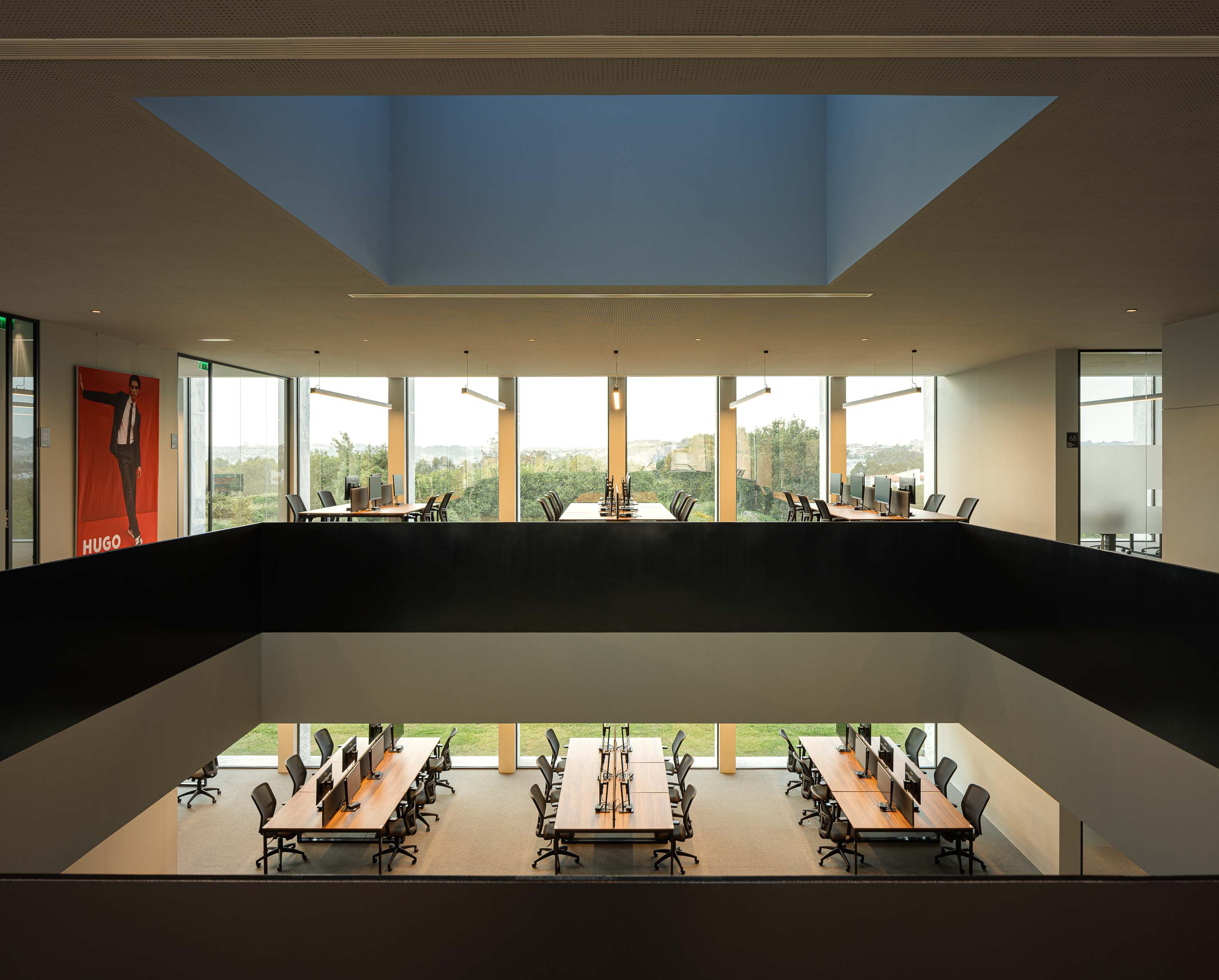 Escritório: Vista superior de um espaço de trabalho com secretárias, cadeiras e iluminação zenital. — Metyis Digital Campus arquitetura UNUM - Oficina de Arquitetura em Gondomar
