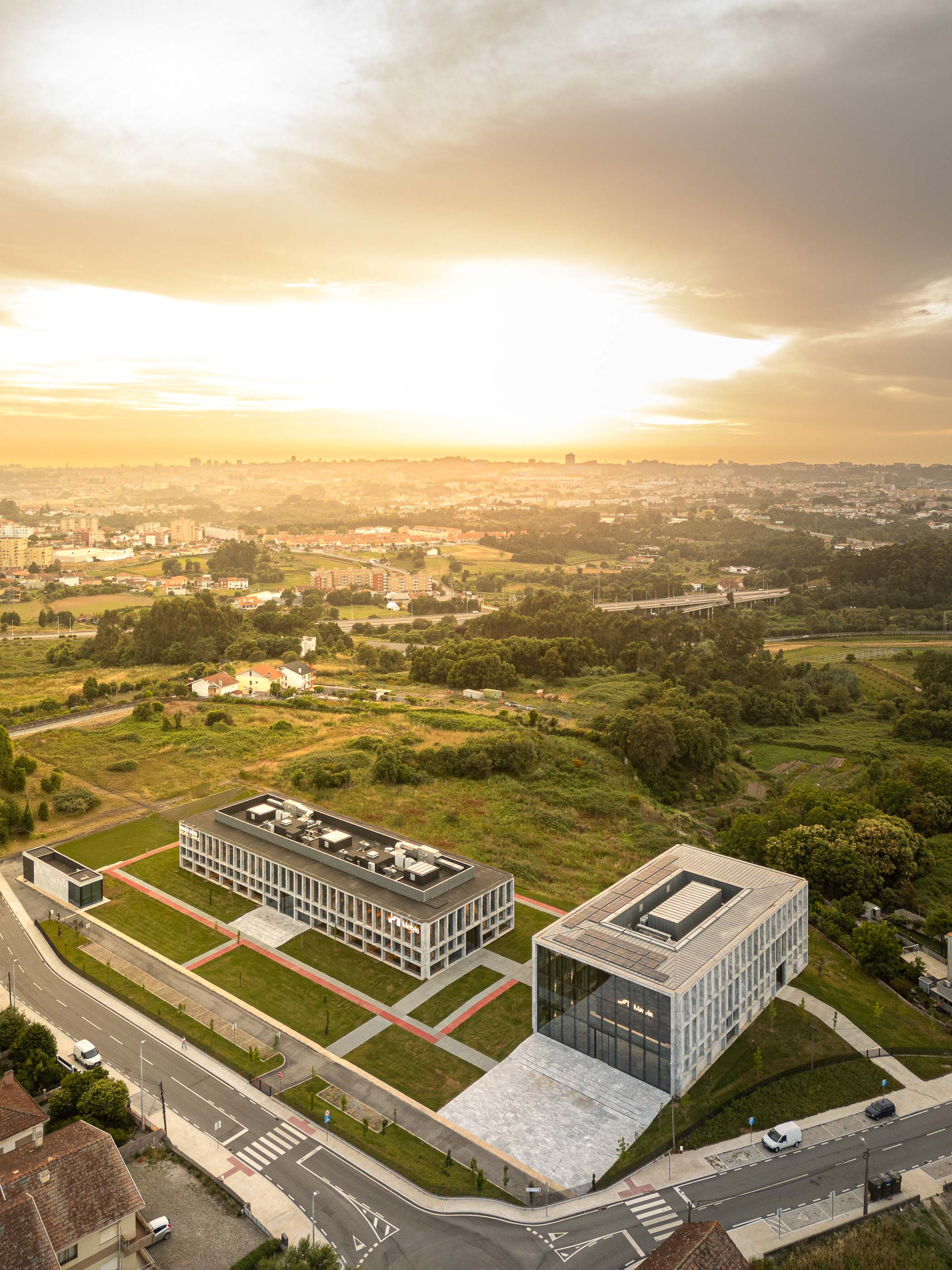 Exterior: Vista aérea do Metyis Digital Campus ao pôr do sol, com a cidade ao fundo. — Metyis Digital Campus arquitetura UNUM - Oficina de Arquitetura em Gondomar