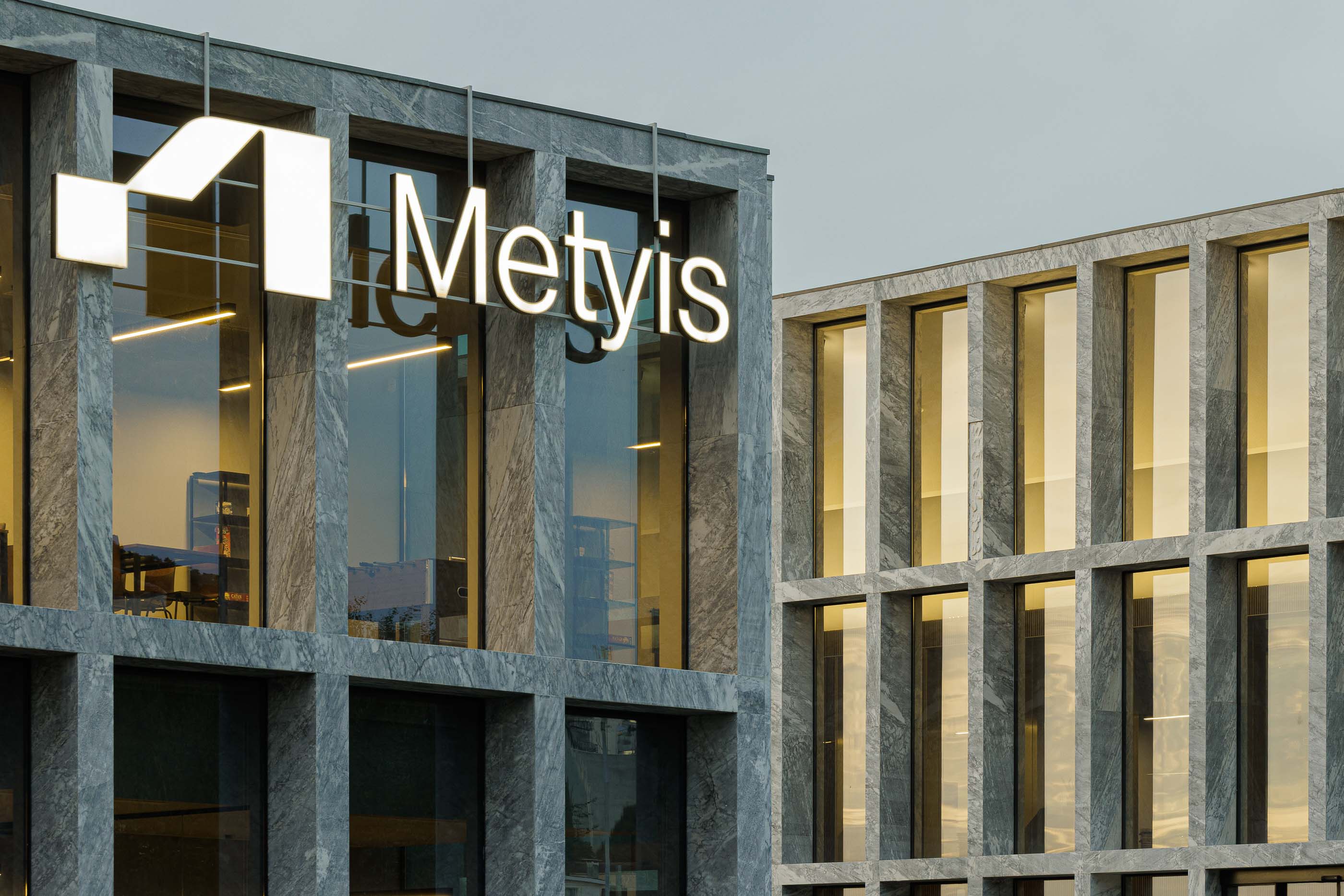 Edifício: Detalhe da fachada em mármore com o logótipo da Metyis iluminado. — Metyis Digital Campus arquitetura UNUM - Oficina de Arquitetura em Gondomar