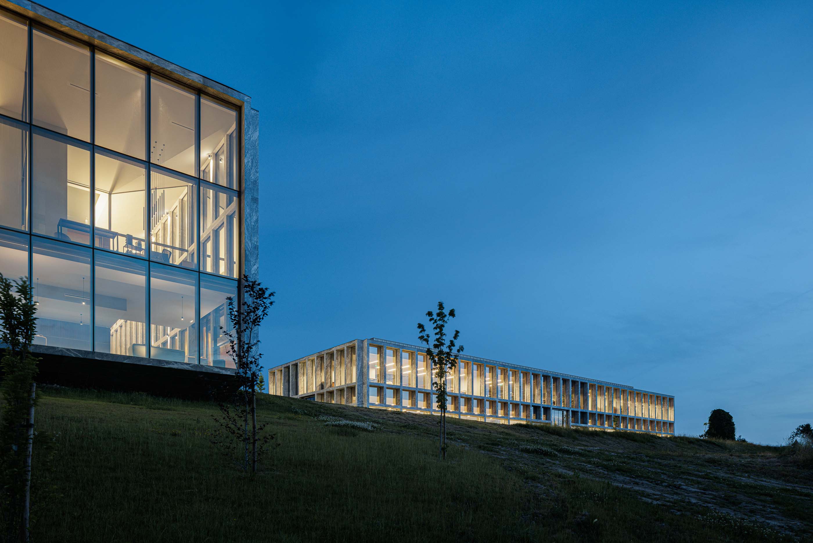 Exterior: Vista noturna dos edifícios iluminados do Metyis Digital Campus. — Metyis Digital Campus arquitetura UNUM - Oficina de Arquitetura em Gondomar