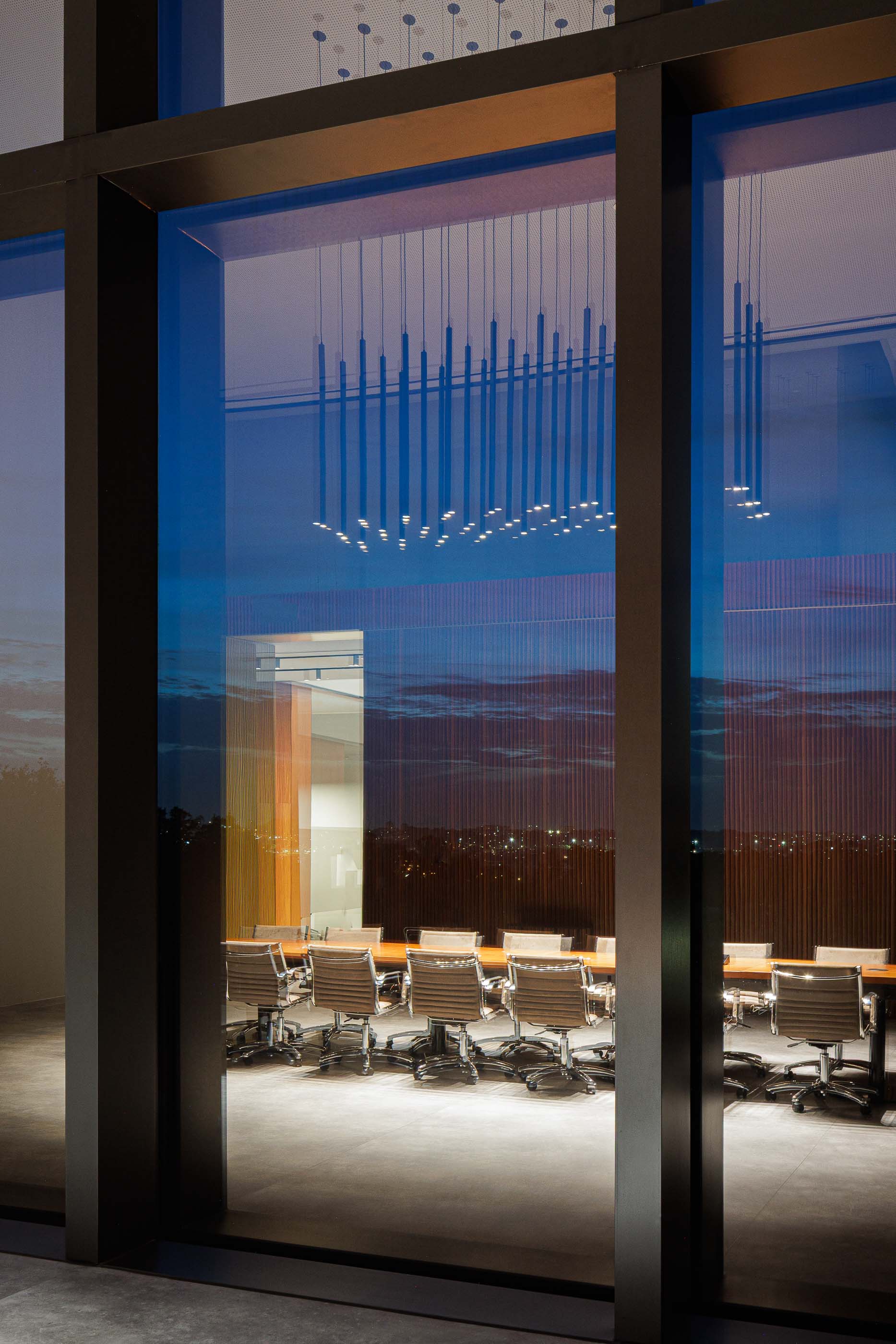 Escritório: Vista de uma sala de reuniões com mesa comprida e cadeiras através de uma janela. — Metyis Digital Campus arquitetura UNUM - Oficina de Arquitetura em Gondomar