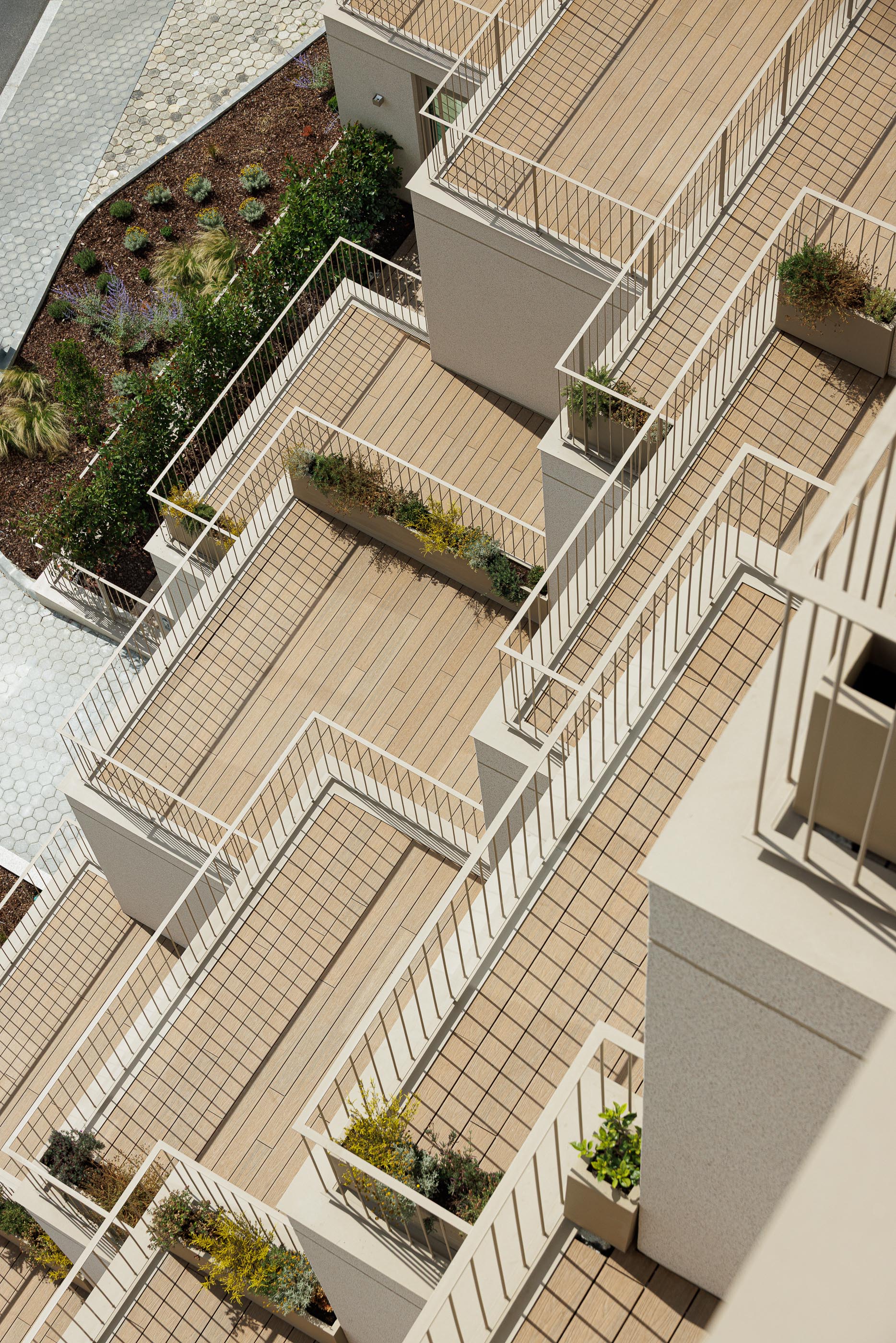 Varandas: Vista superior das varandas escalonadas com pavimento em madeira e floreiras. — Macau Valley arquitetura hori-zonte em Vila Nova de Gaia