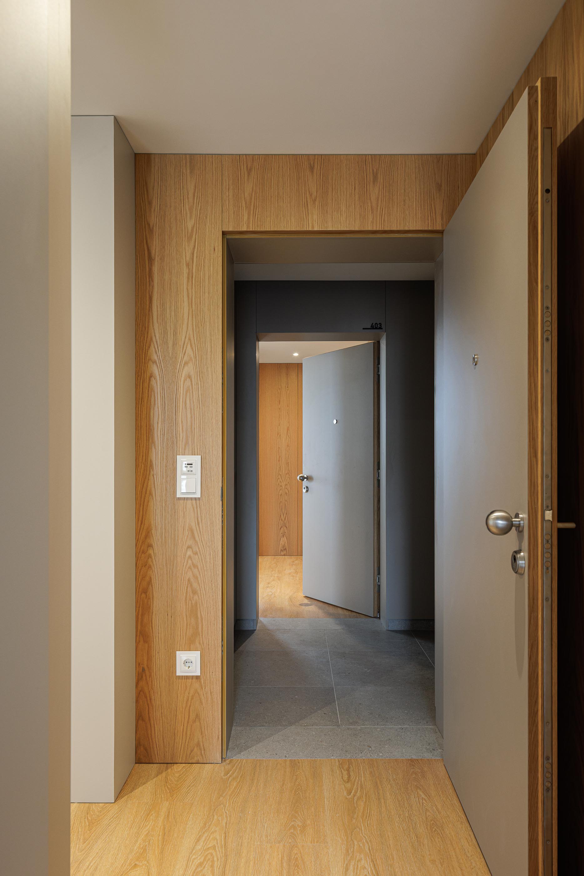 Entrada: Hall de entrada do apartamento com revestimento em madeira e pavimento cerâmico. — Macau Valley arquitetura hori-zonte em Vila Nova de Gaia