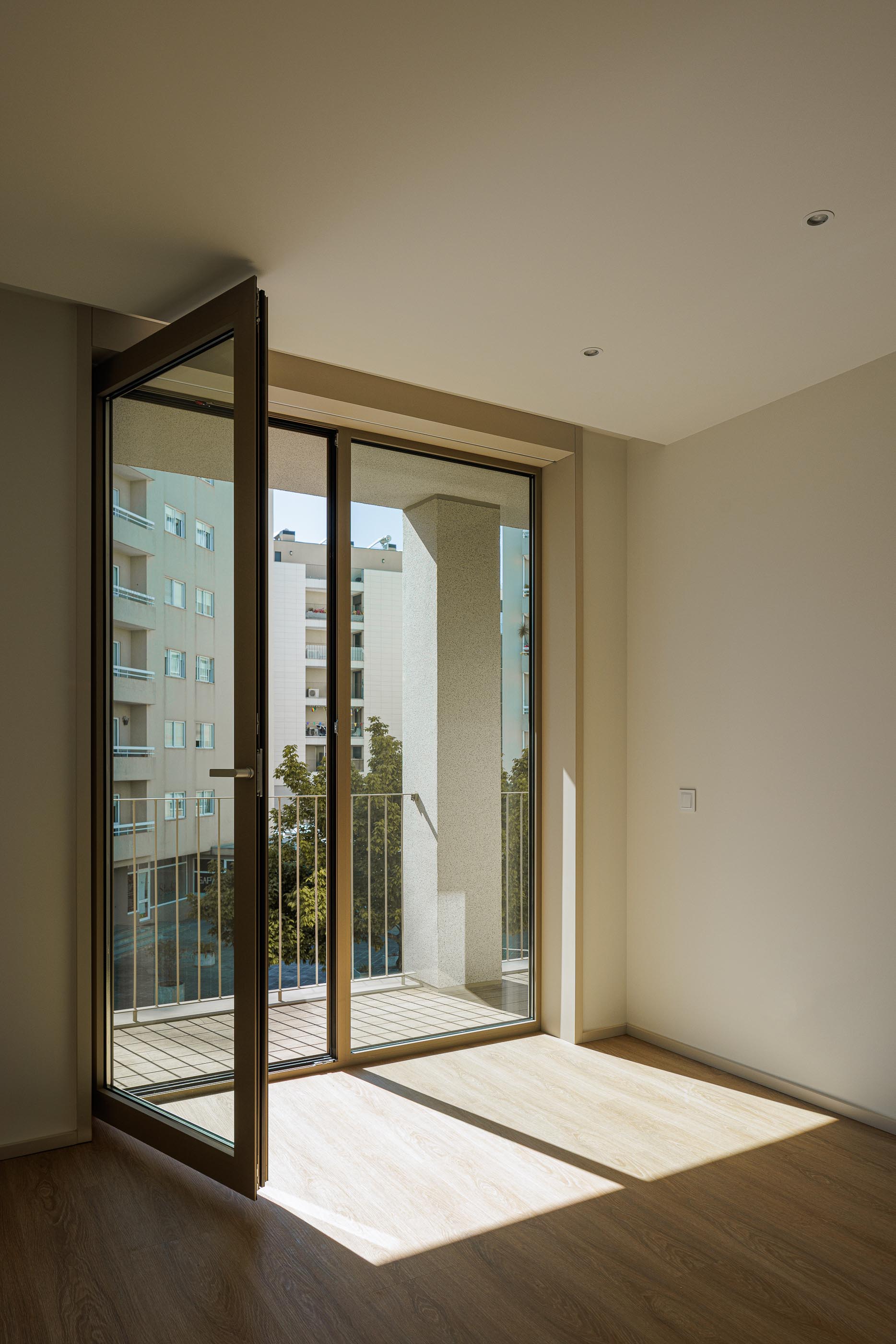 Quarto: Quarto com pavimento em madeira e acesso à varanda com caixilharia castanha. — Macau Valley arquitetura hori-zonte em Vila Nova de Gaia