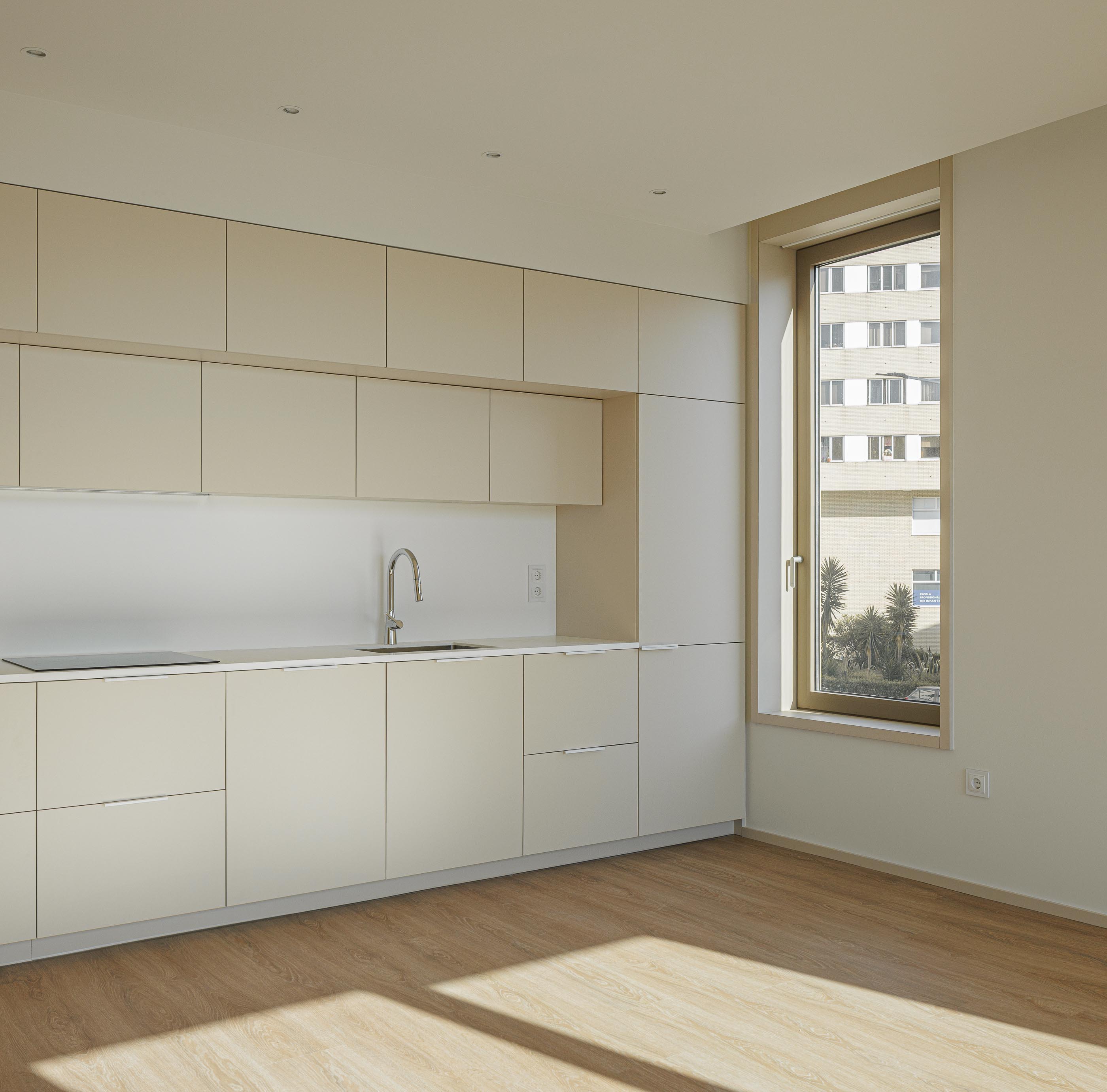 Cozinha: Cozinha com armários bege, bancada branca e pavimento em madeira. — Macau Valley arquitetura hori-zonte em Vila Nova de Gaia