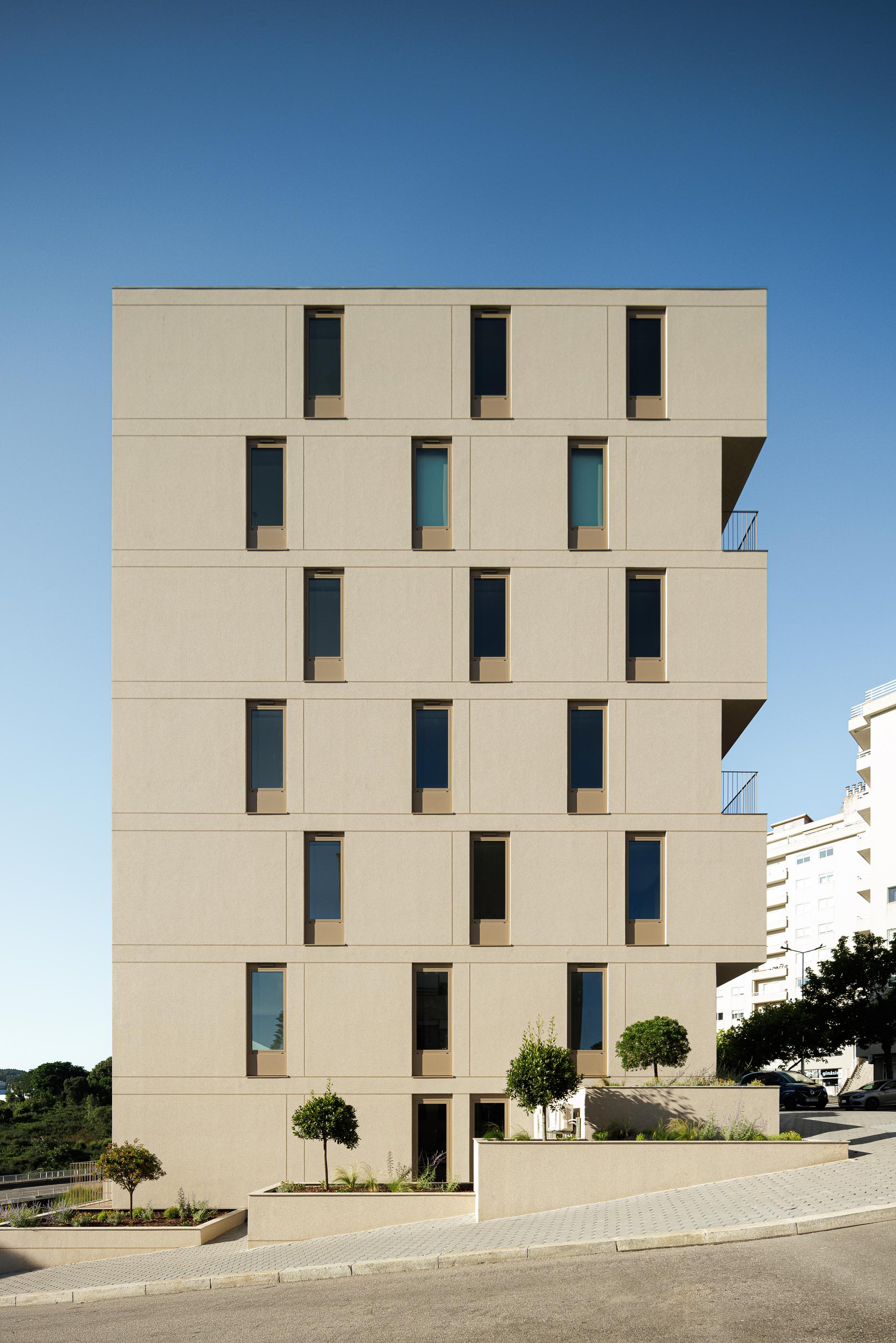 Fachada: Edifício de apartamentos com fachada bege texturada e janelas verticais. — Macau Valley arquitetura hori-zonte em Vila Nova de Gaia