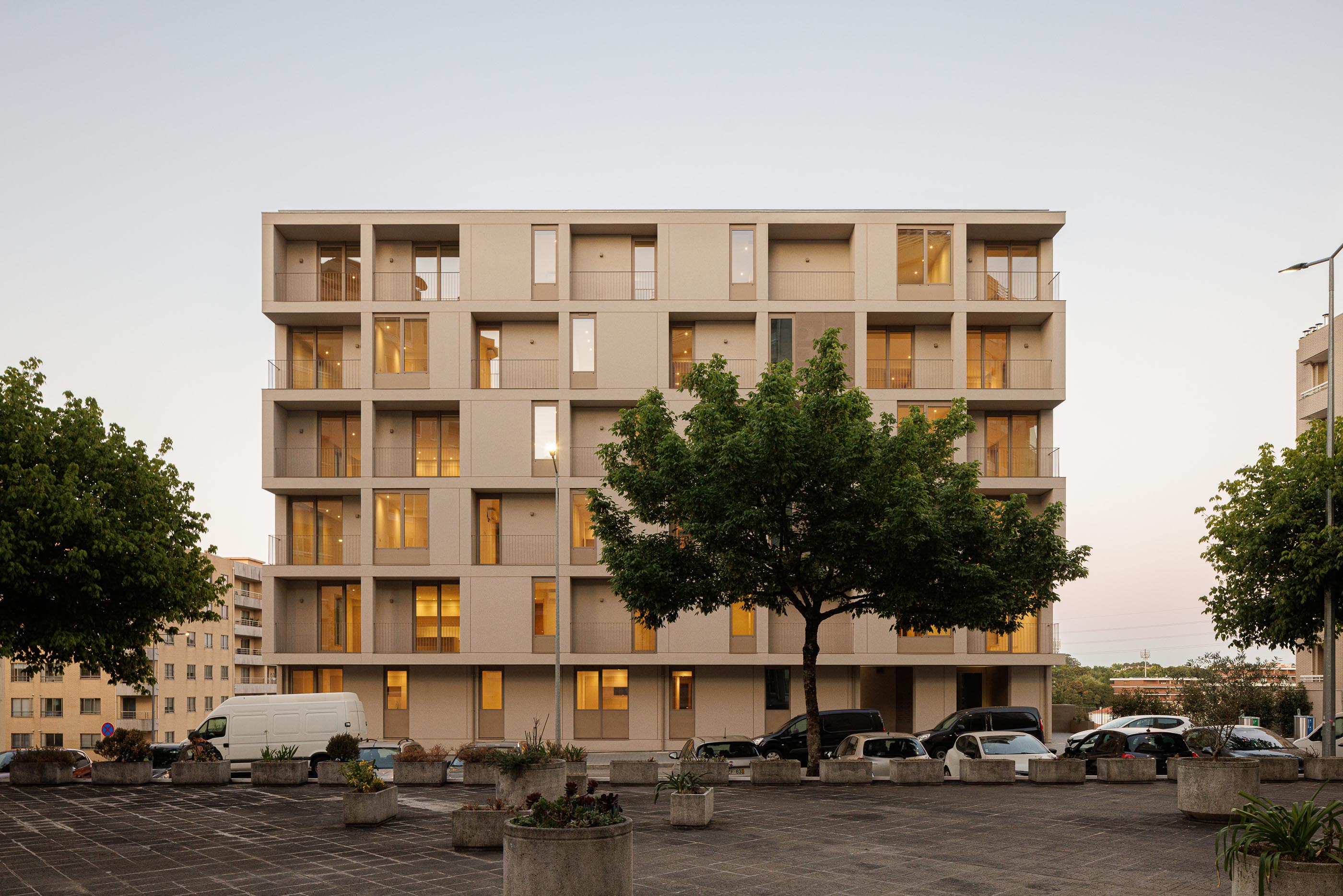 Fachada: Edifício de apartamentos com varandas escalonadas e edifícios vizinhos ao entardecer. — Macau Valley arquitetura hori-zonte em Vila Nova de Gaia
