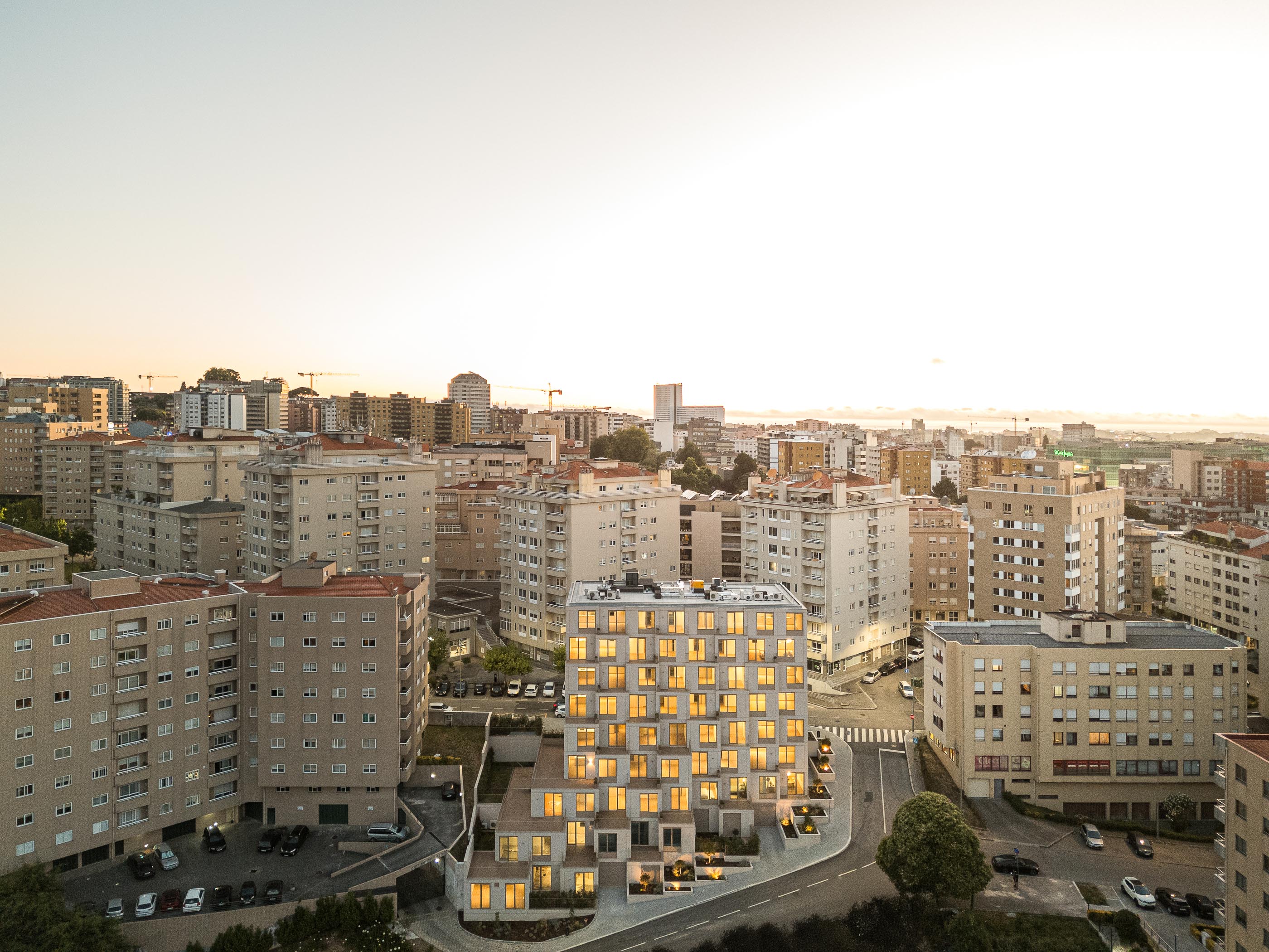 Fachada: Edifício de apartamentos com varandas escalonadas e jardins frontais ao anoitecer. — Macau Valley arquitetura hori-zonte em Vila Nova de Gaia