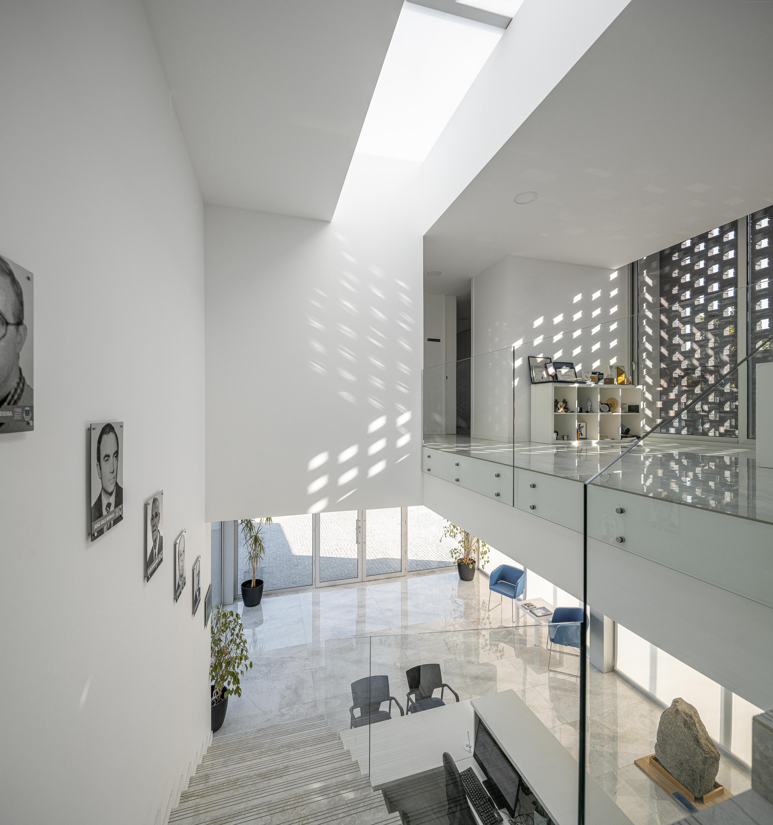 Hall: Vista superior do hall de entrada com escadas, balcão de atendimento e claraboia, com pavimento em mármore. — Junta de Freguesia de Vermoim arquitetura Rui Mendes Ribeiro Arquitecto em Vila Nova de Famalicão