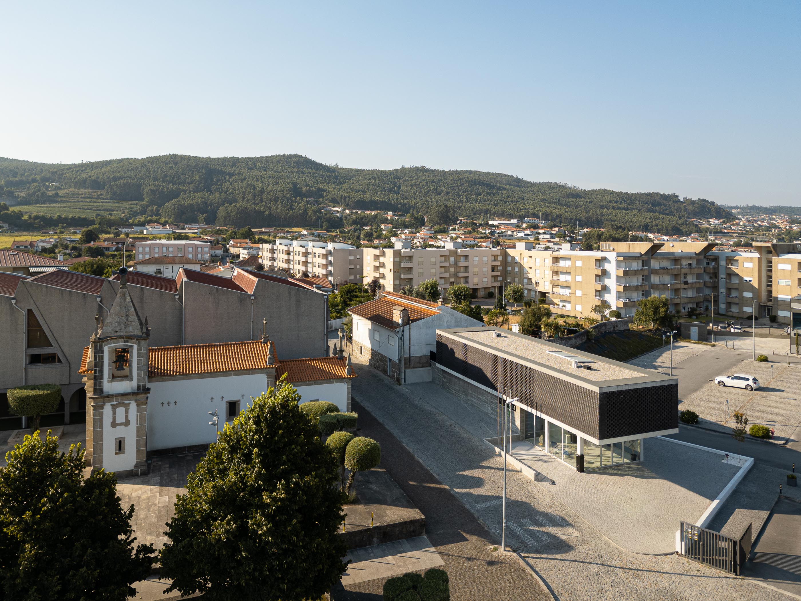 Exterior: Vista aérea da Junta de Freguesia, da igreja matriz e da paisagem urbana circundante. — Junta de Freguesia de Vermoim arquitetura Rui Mendes Ribeiro Arquitecto em Vila Nova de Famalicão