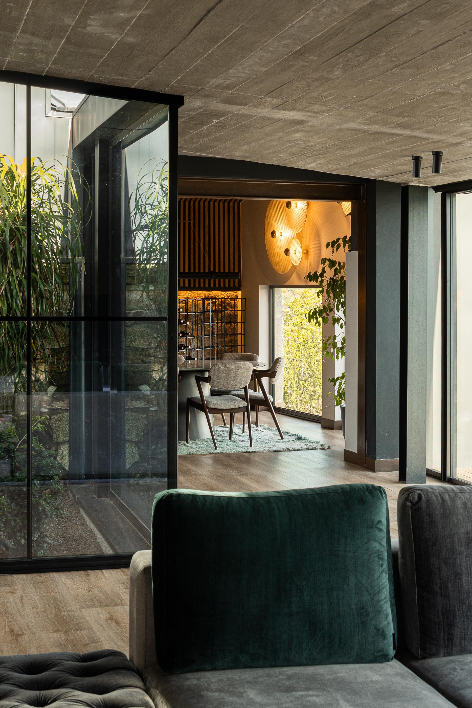 Sala de estar: Detalhe do sofá, vista para o jardim interior e sala de jantar. — Moradia do Retiro arquitetura Ricardo Azevedo Arquitecto em Santo Tirso