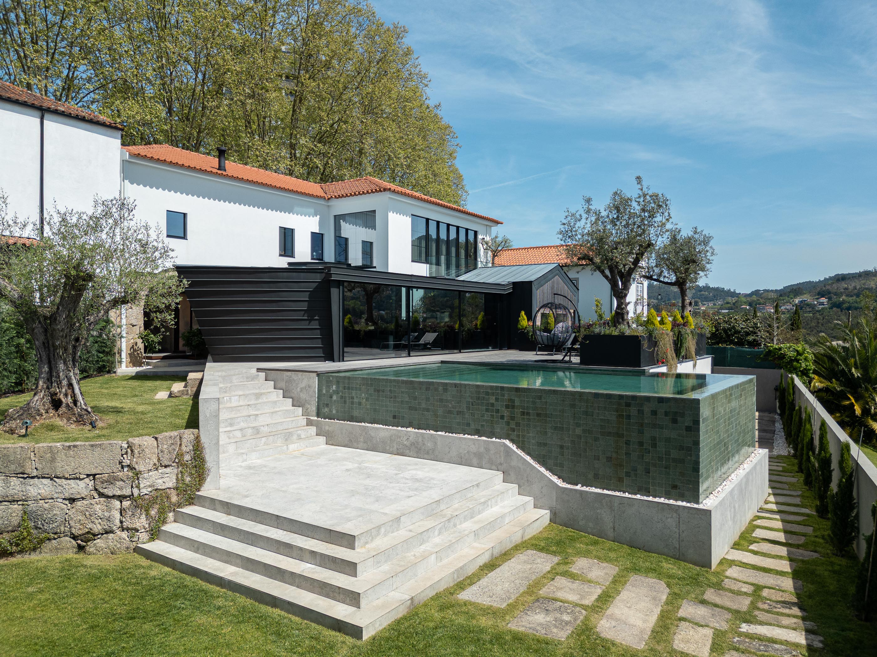 Exterior: Vista da moradia com piscina, anexo moderno, terraço e jardim. — Moradia do Retiro arquitetura Ricardo Azevedo Arquitecto em Santo Tirso