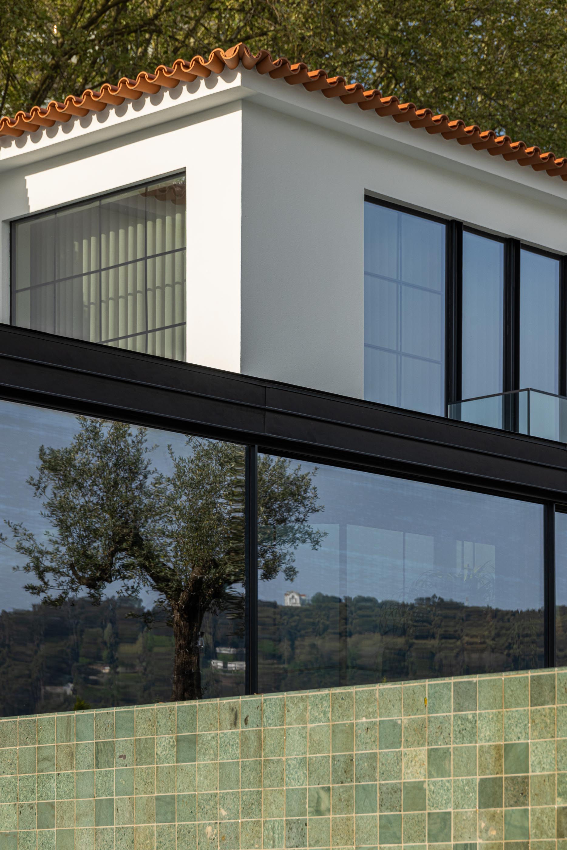 Exterior: Detalhe da fachada da moradia, anexo moderno e piscina com mosaicos verdes. — Moradia do Retiro arquitetura Ricardo Azevedo Arquitecto em Santo Tirso