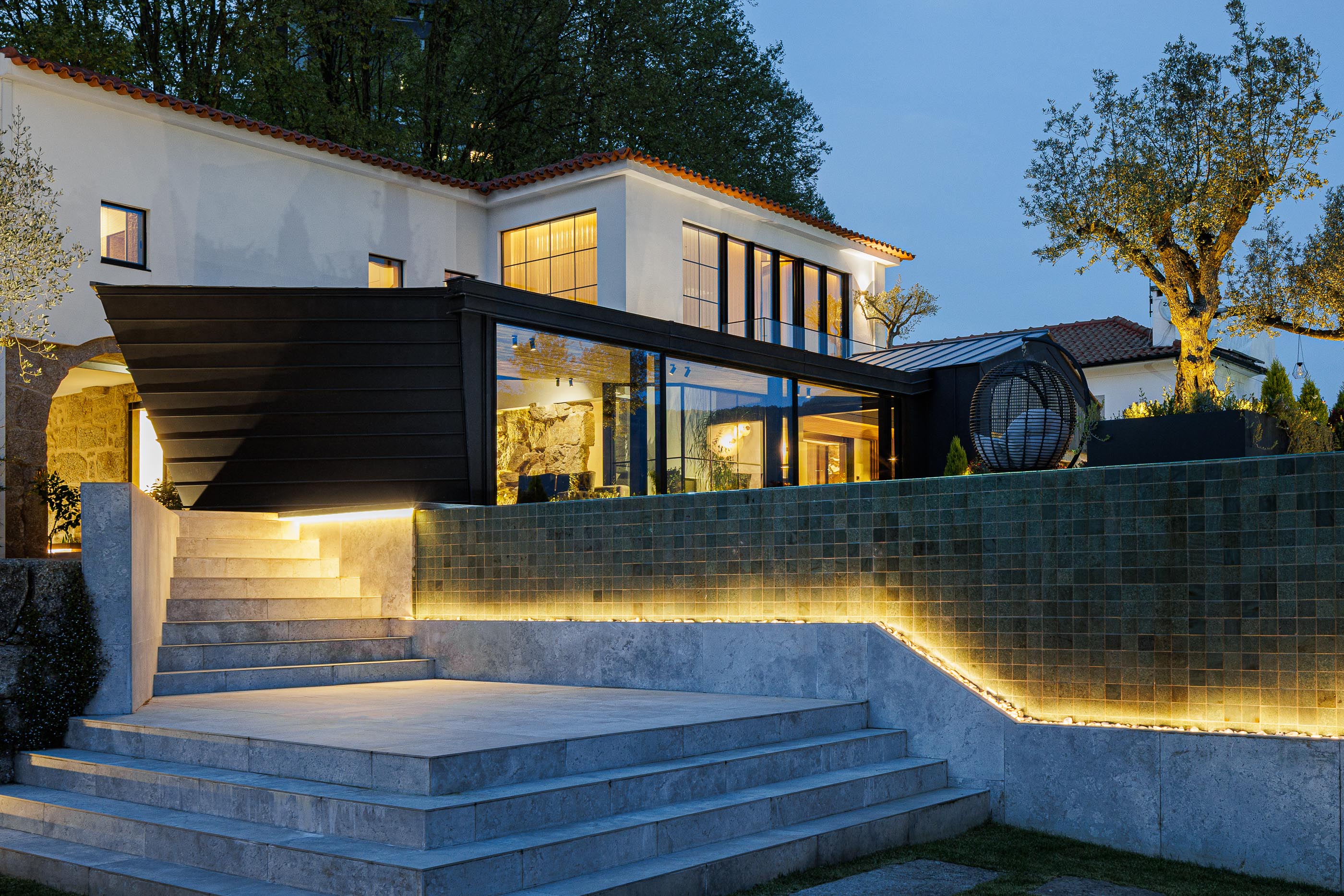 Exterior: Vista noturna da moradia com iluminação na piscina, terraço e anexo moderno. — Moradia do Retiro arquitetura Ricardo Azevedo Arquitecto em Santo Tirso
