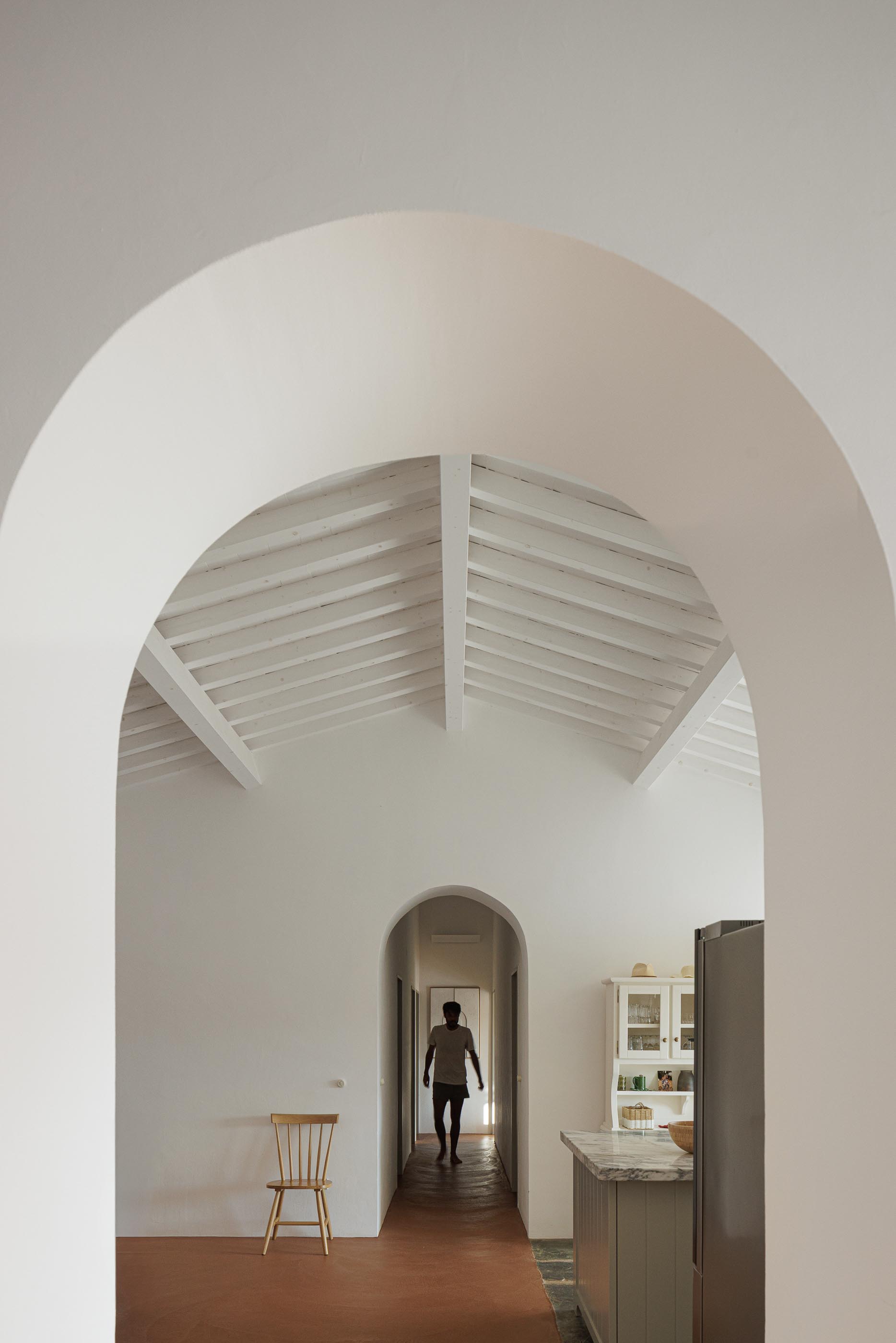 Hall: Vista em perspectiva com arcos, pavimento em tijoleira e teto branco com vigas de madeira. — Monte do Divor arquitetura Vasco Burnay Arquitectura em Estremoz