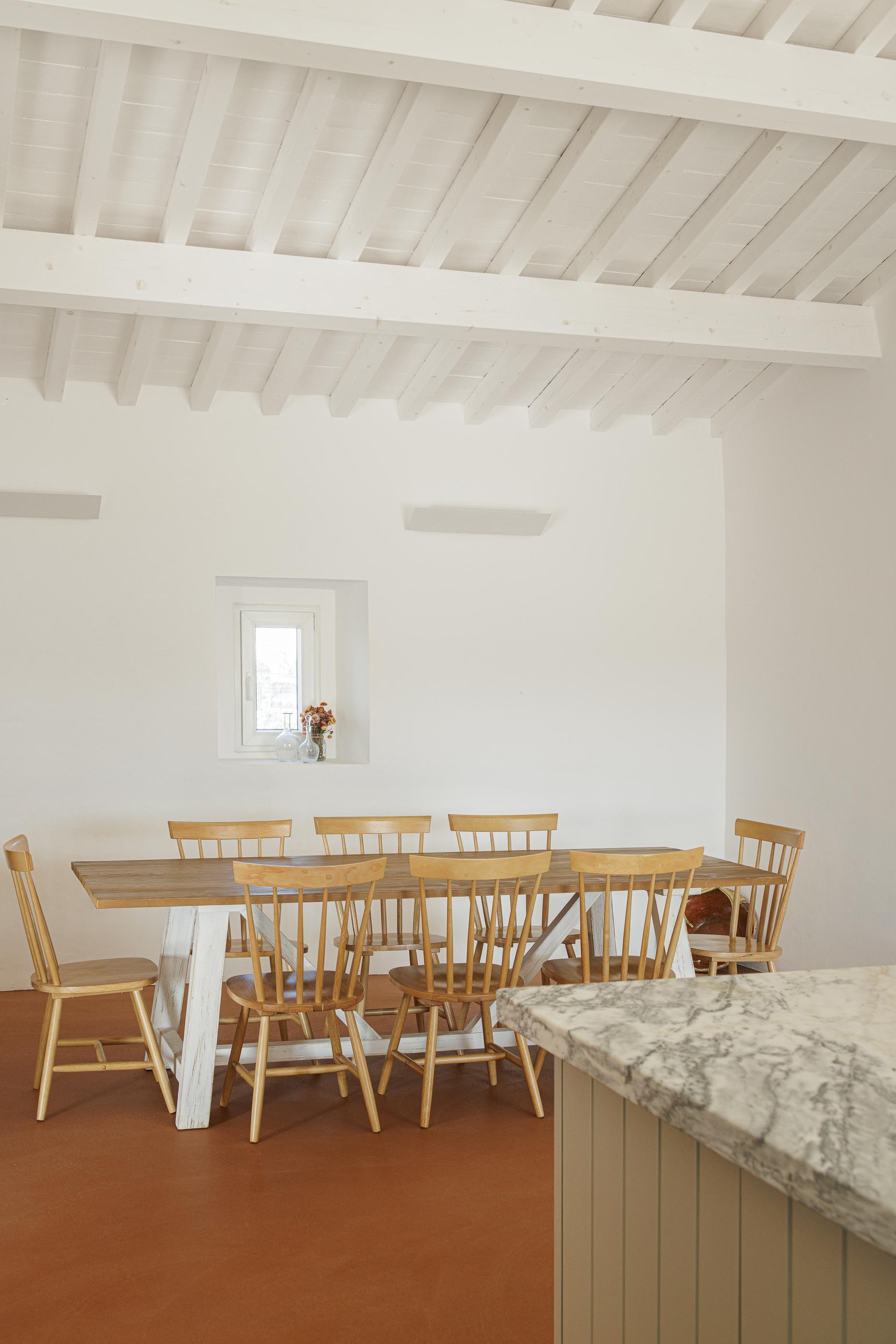 Sala de jantar: Mesa de madeira com cadeiras, pavimento em tijoleira e teto branco com vigas de madeira. — Monte do Divor arquitetura Vasco Burnay Arquitectura em Estremoz