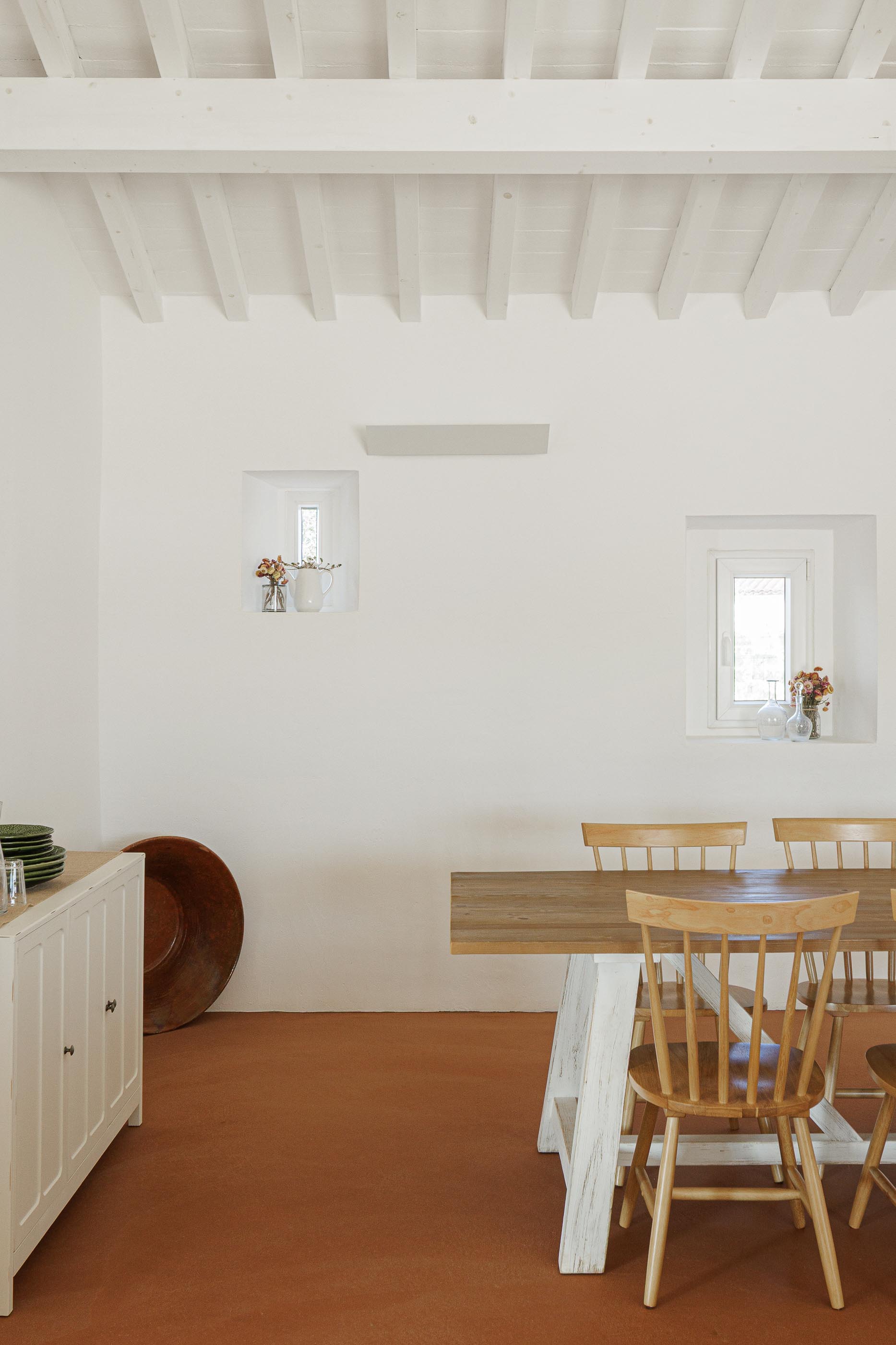 Sala de jantar: Mesa de madeira com cadeiras, pavimento em tijoleira e teto branco com vigas de madeira. — Monte do Divor arquitetura Vasco Burnay Arquitectura em Estremoz