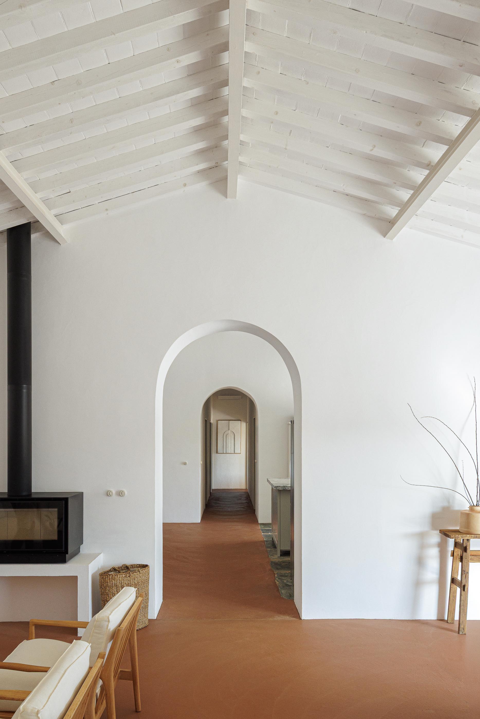 Hall: Vista em perspectiva com arcos, pavimento em tijoleira e teto branco com vigas de madeira. — Monte do Divor arquitetura Vasco Burnay Arquitectura em Estremoz