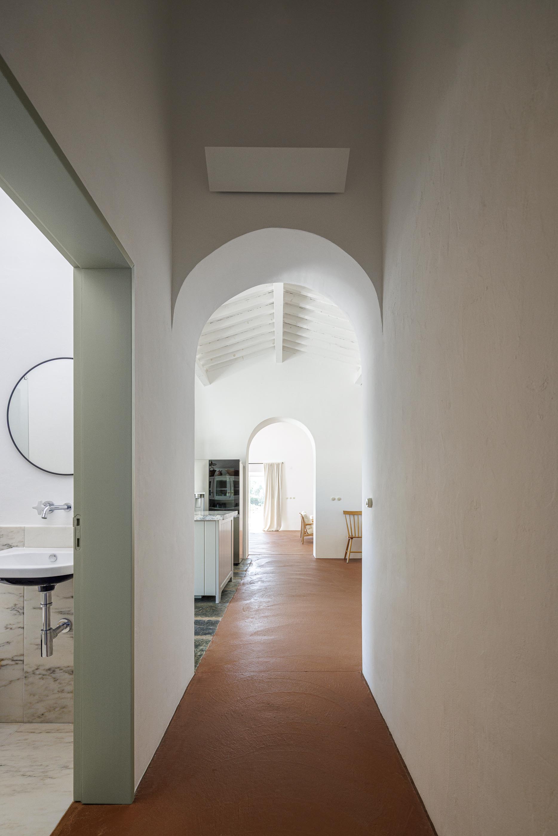 Corredor: Vista para a casa de banho e sala de estar, com pavimento em tijoleira. — Monte do Divor arquitetura Vasco Burnay Arquitectura em Estremoz