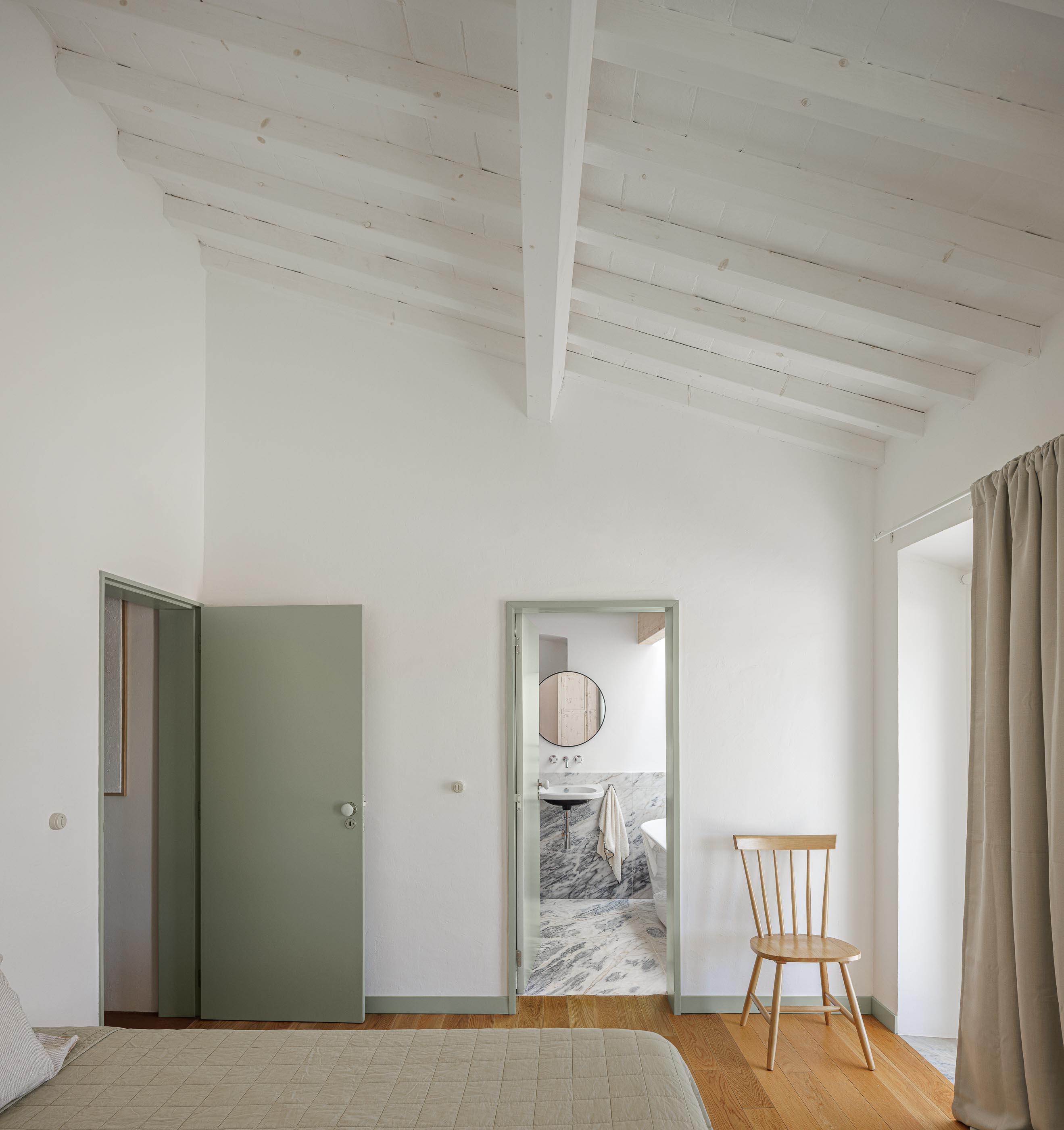 Quarto: Cama de casal, pavimento em madeira e porta para a casa de banho. — Monte do Divor arquitetura Vasco Burnay Arquitectura em Estremoz
