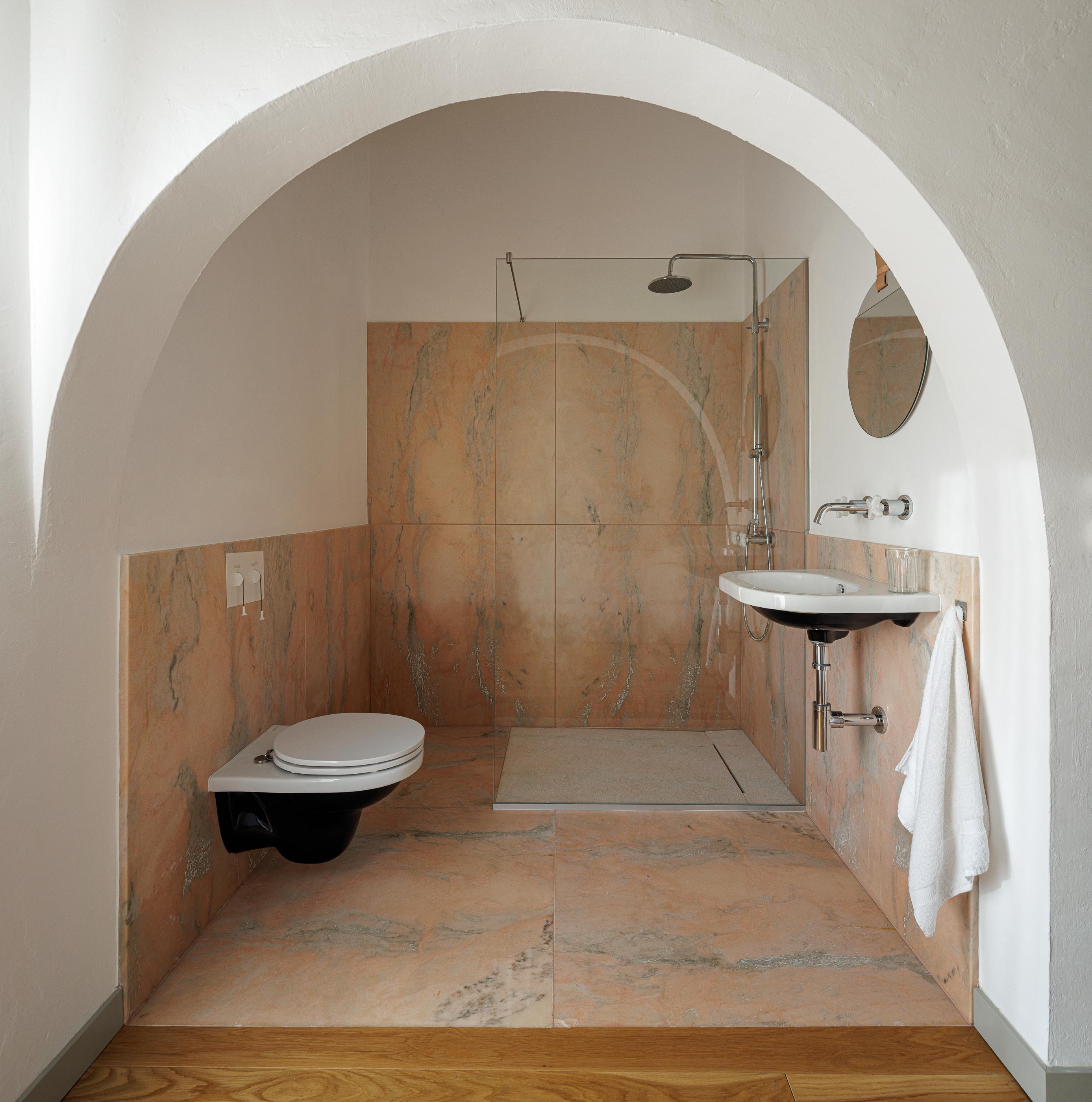 Casa de banho: Duche, lavatório suspenso, sanita suspensa e revestimento em mármore rosa. — Monte do Divor arquitetura Vasco Burnay Arquitectura em Estremoz
